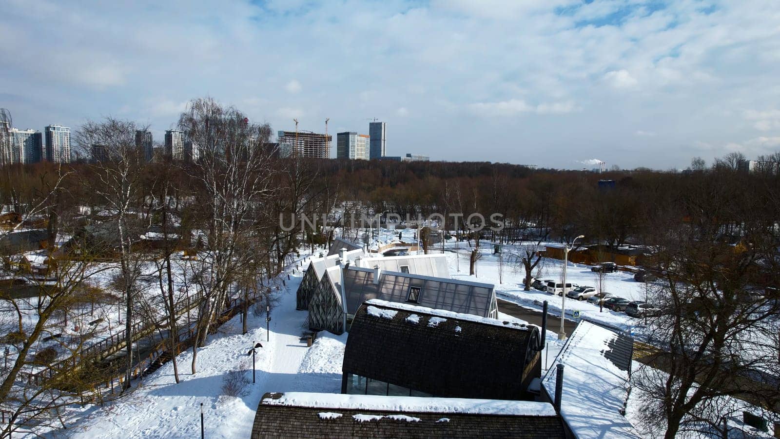 Top view of suburb with greenhouses on winter day. Creative. Suburban infrastructure on background of horizon with modern city. Agriculture and cottage settlement in suburbs on sunny winter day.