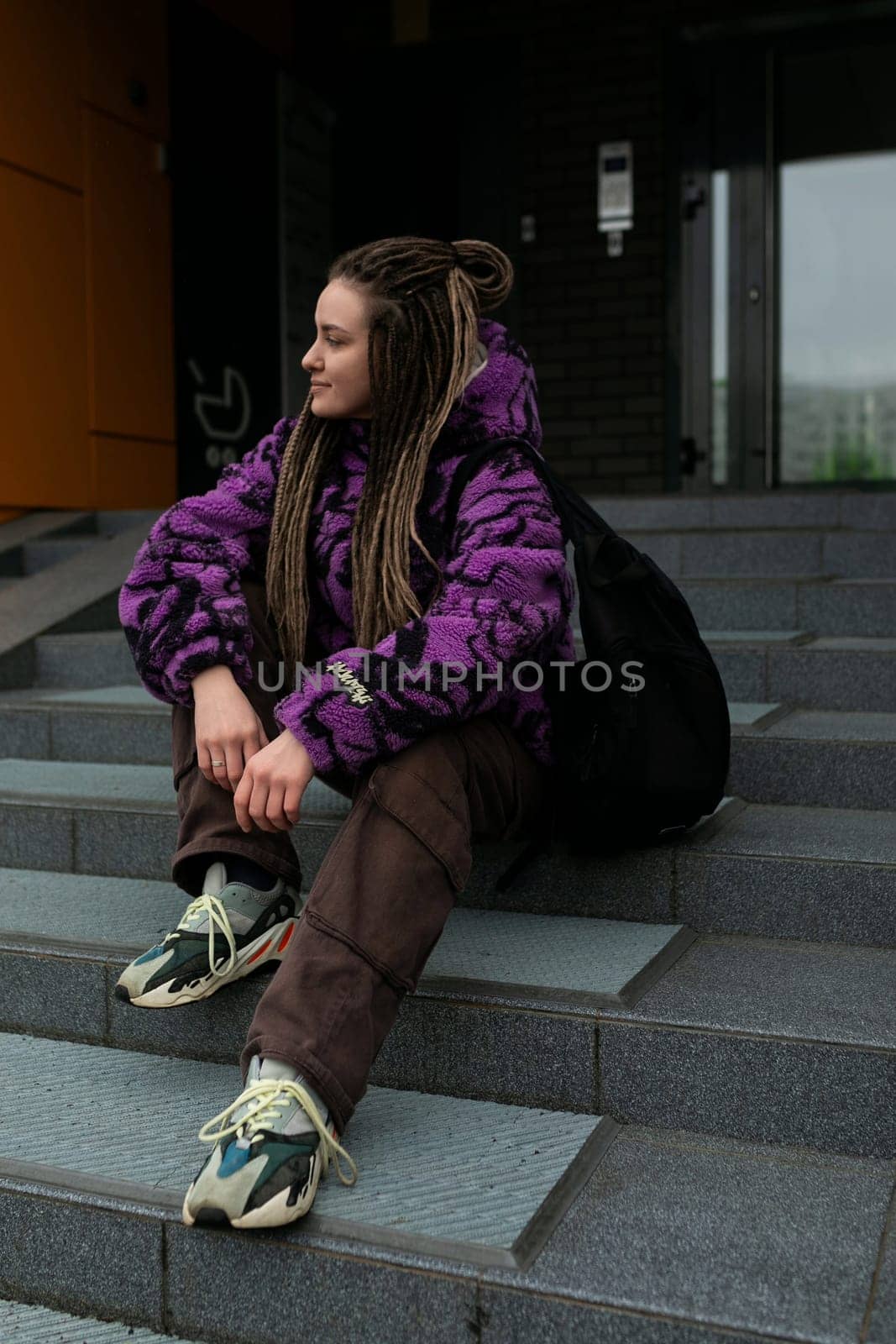 Beautiful young woman with dreadlocks and piercings walks through the city.