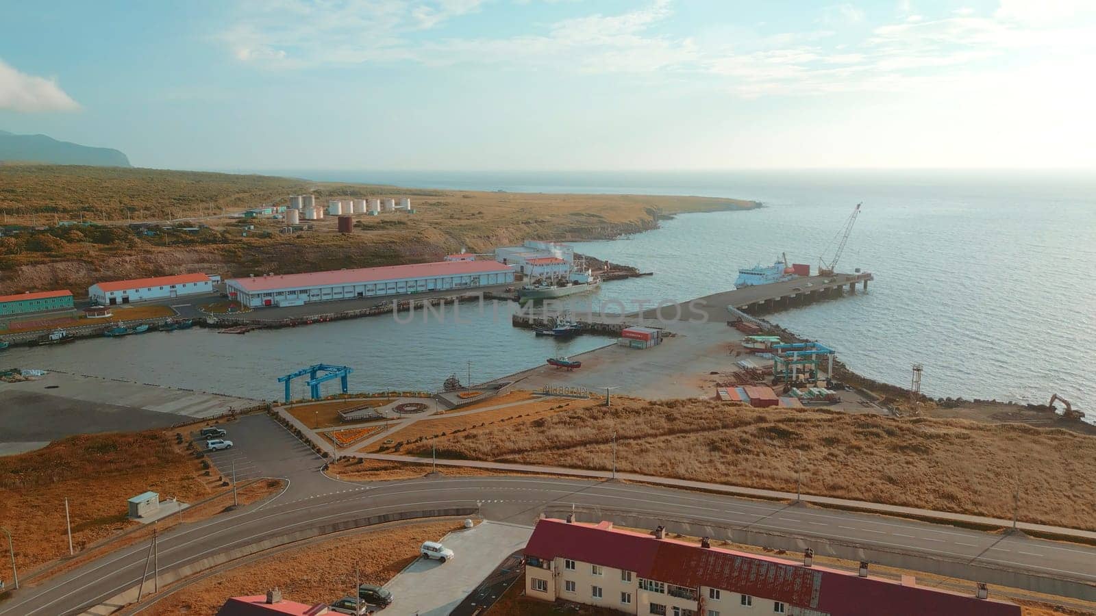Top view of sea port with sand on north coast. Clip. infrastructure of seaport on seashore. Beautiful landscape of village with seaport on coast of mountain coast.