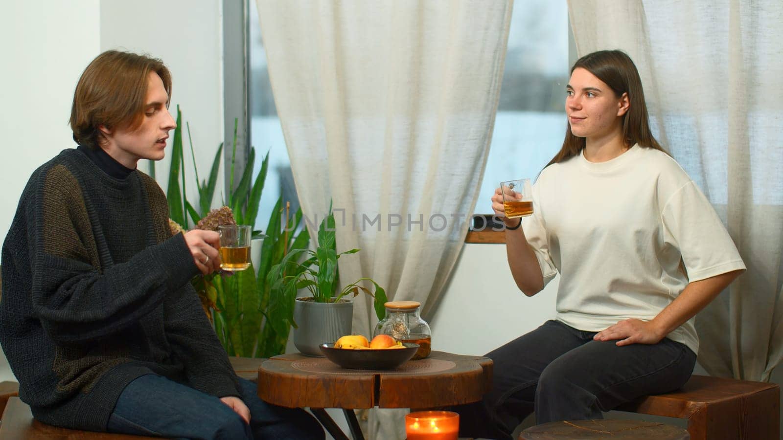 Students communicate and drink tea in cafe. Media. Young man and woman are drinking tea and talking in cafe. Cheerful conversation between young couple of students in cozy cafe.