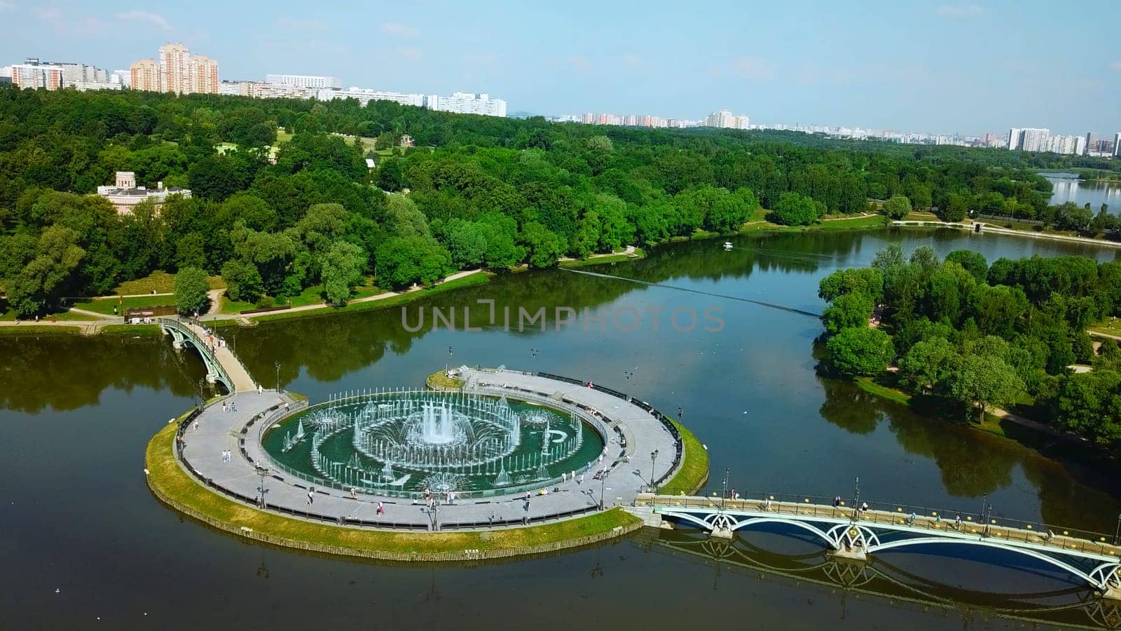 Top view of bridges in city pond with fountains. Creative. Island with bridges and fountains in city pond. Beautiful fountain complex on river island with pedestrian bridges.