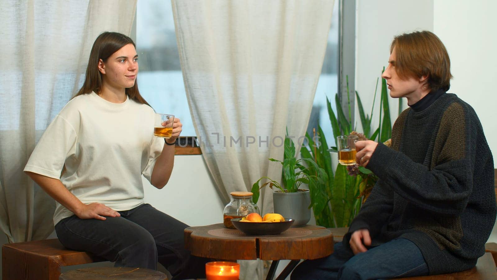 Students communicate and drink tea in cafe. Media. Young man and woman are drinking tea and talking in cafe. Cheerful conversation between young couple of students in cozy cafe.