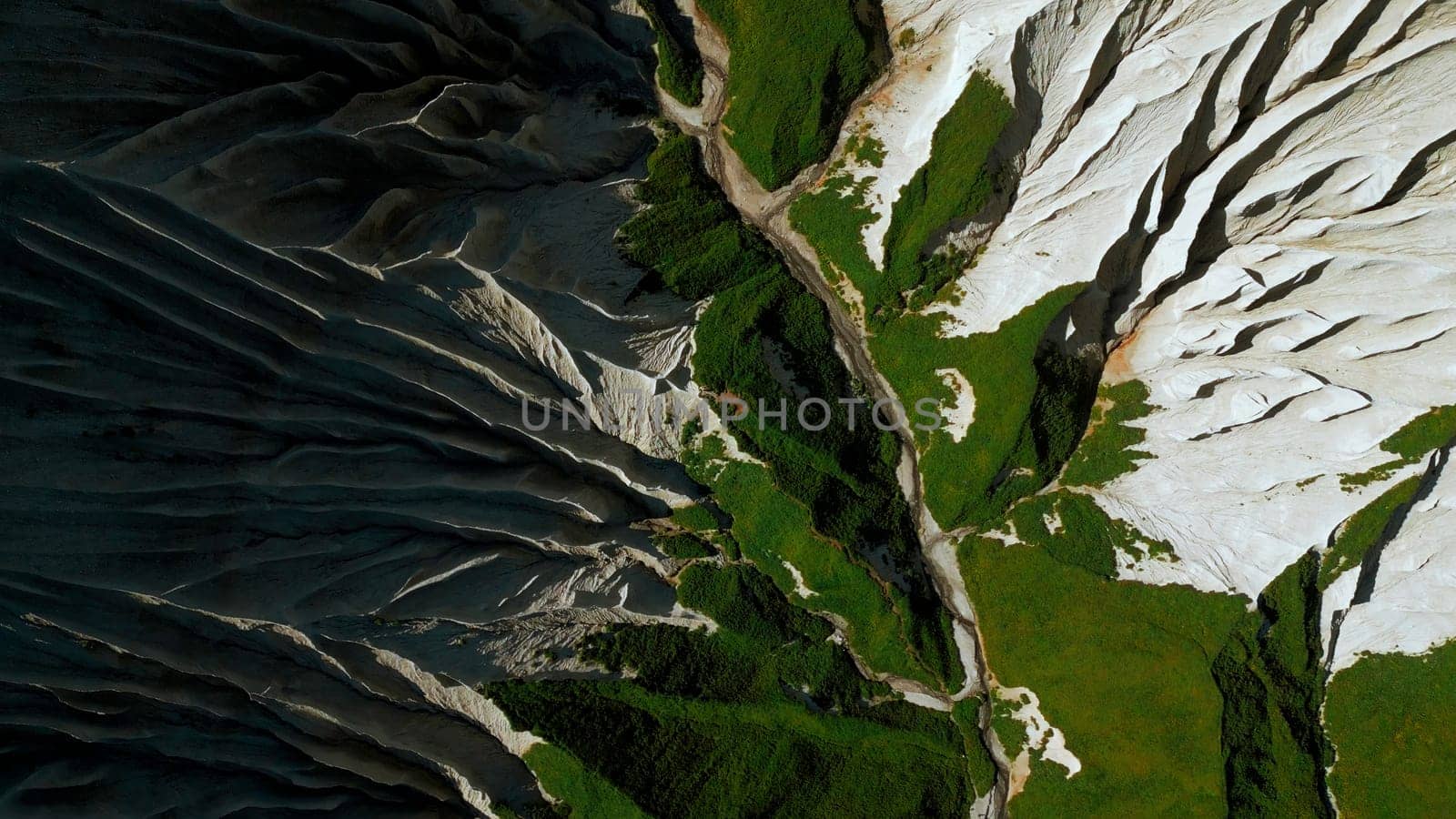 Aerial top down view of a mountain top. Clip. Green summer grass and white stony slopes