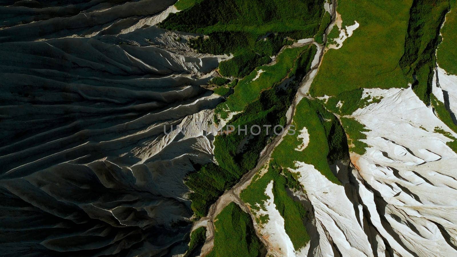 Aerial top down view of a mountain top. Clip. Green summer grass and white stony slopes