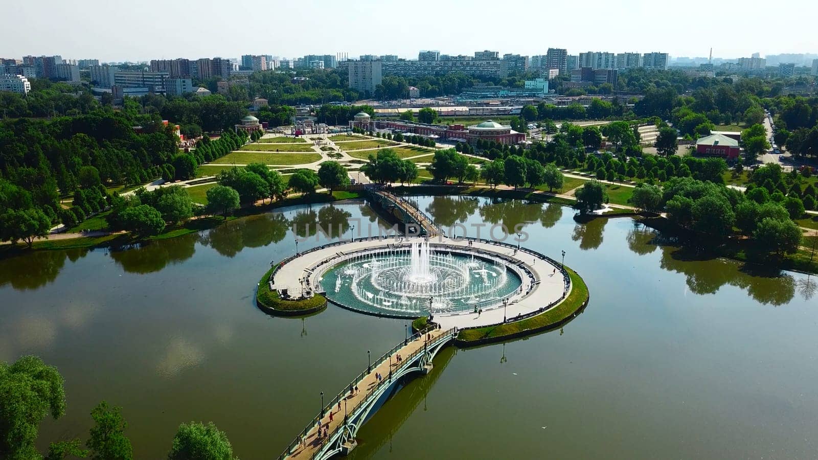 Top view of fountain in pond and historical palace. Creative. Amazing fountain in lake with pedestrian bridges at historical palace. Historical complex with fountains, gardens and buildings.