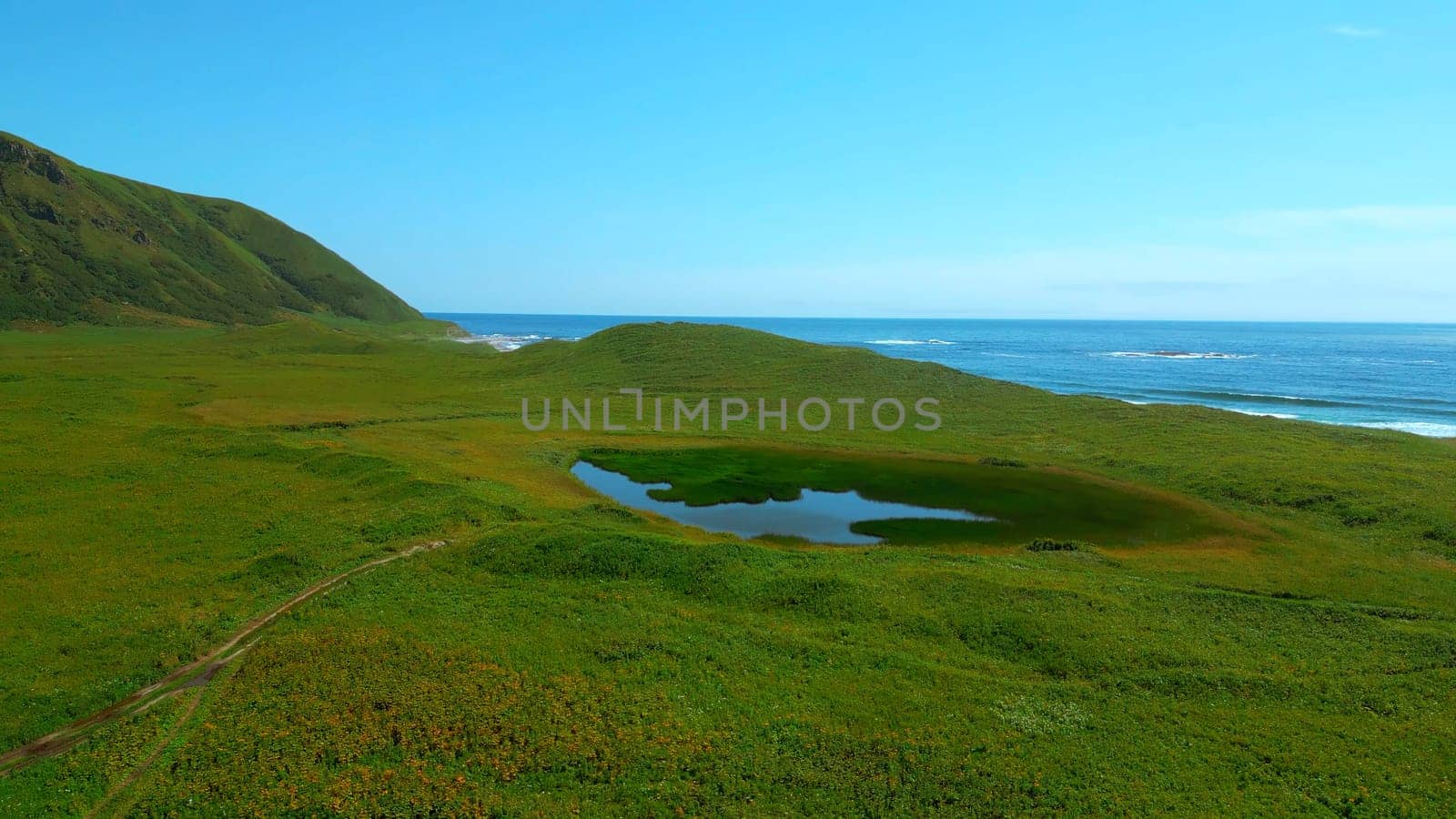 Panoramic aerial shot of a sunny coastal landscape in Spain. Clip. Green meadow highlands and sea shore