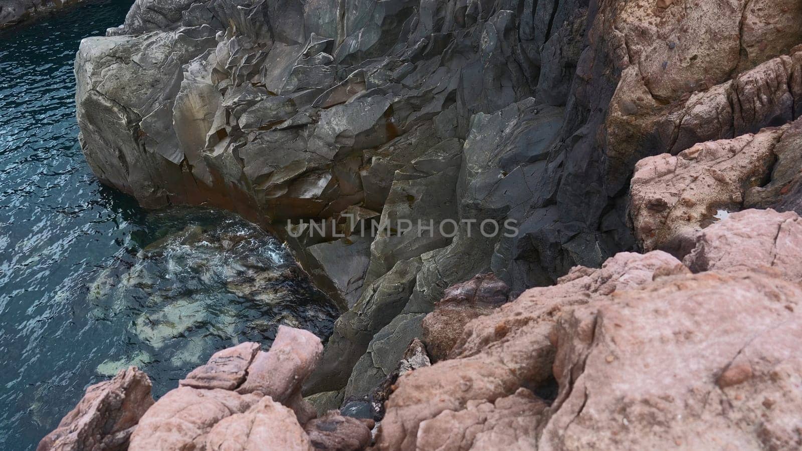 View of dangerous stone cliffs near sea water. Clip. On edge of dizzying cliffs by sea water. Beautiful and dangerous sharp rocks with sea water.