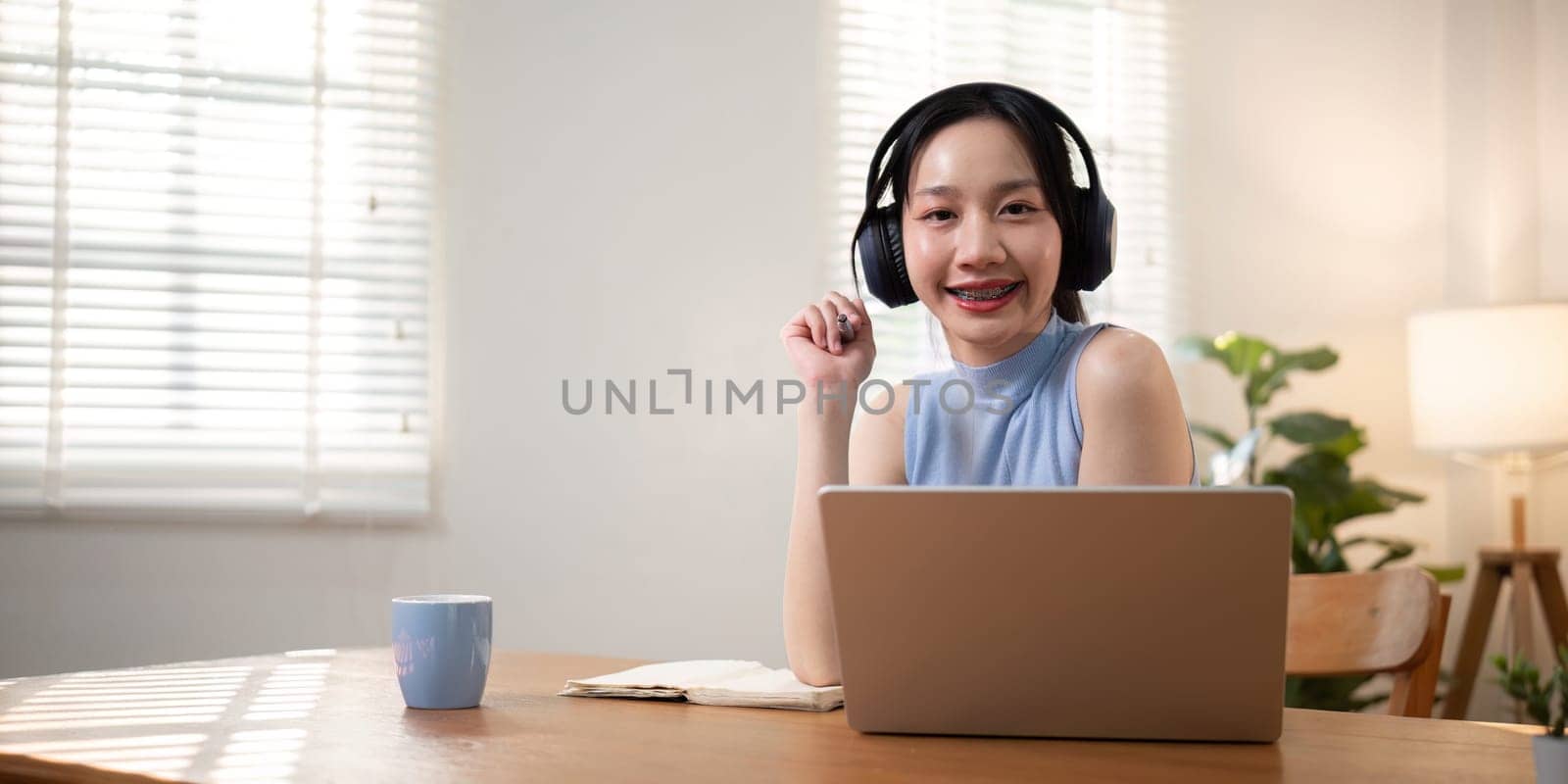 Happy young woman asian in headphones and laptop, girl student talking by video conference call, online training by nateemee