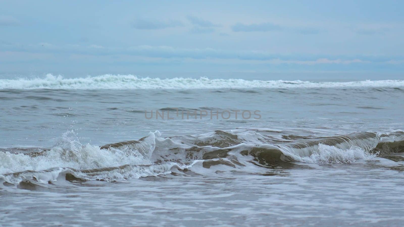 Seascape of beautiful waves on cloudy day. Clip. Beautiful coastal waves on background of horizon with cloudy sky. Coastal waves of North Sea on cloudy day by Mediawhalestock
