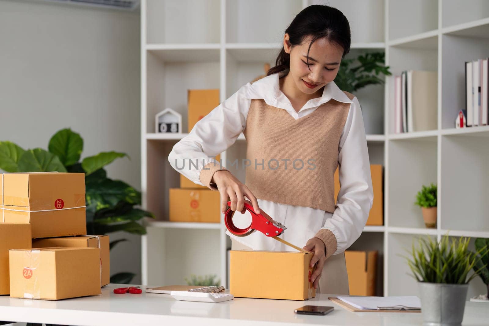 Young business entrepreneur sealing a box with tape. Preparing for shipping, Packing, online selling, e-commerce concept by itchaznong