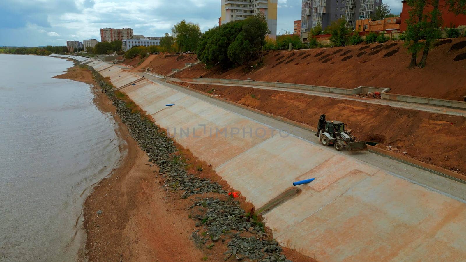Construction and strengthening of a new safety embankment along the river. Clip. Aerial view ov the improving city area