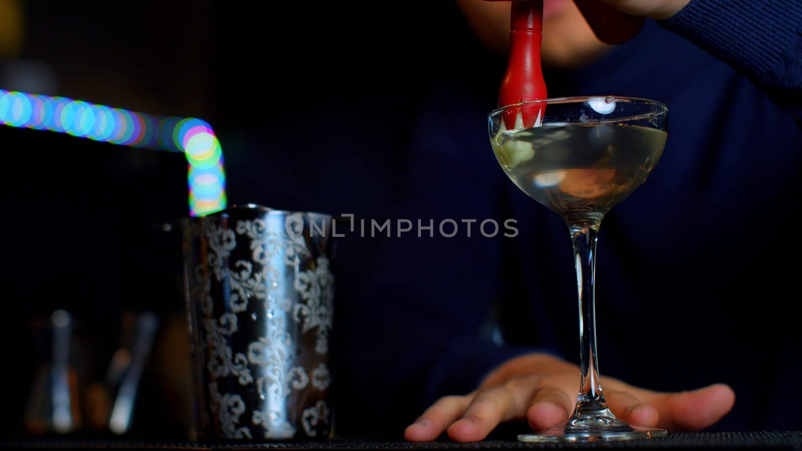 A professional bartender preparing an alcoholic cocktail with cream topping. Media. Making a beverage at the bar or disco club. by Mediawhalestock