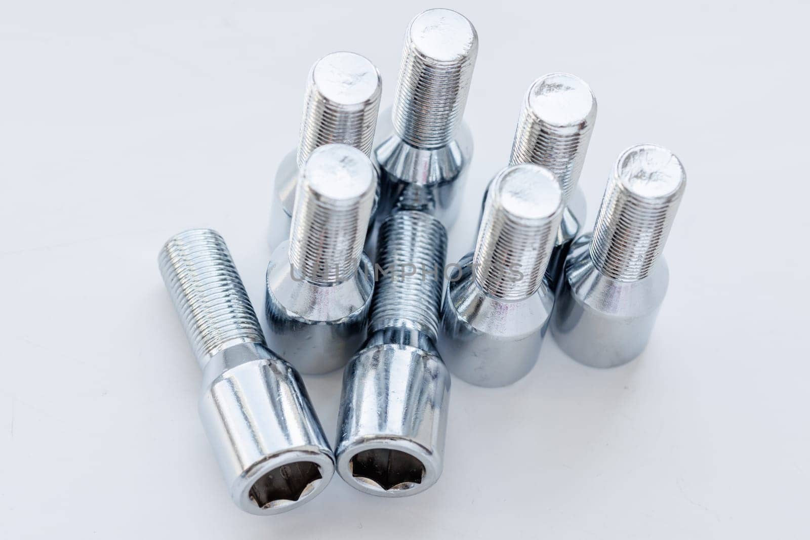 shiny steel chrome coated wheel bolts on white background, full-frame closeup high angle view by z1b