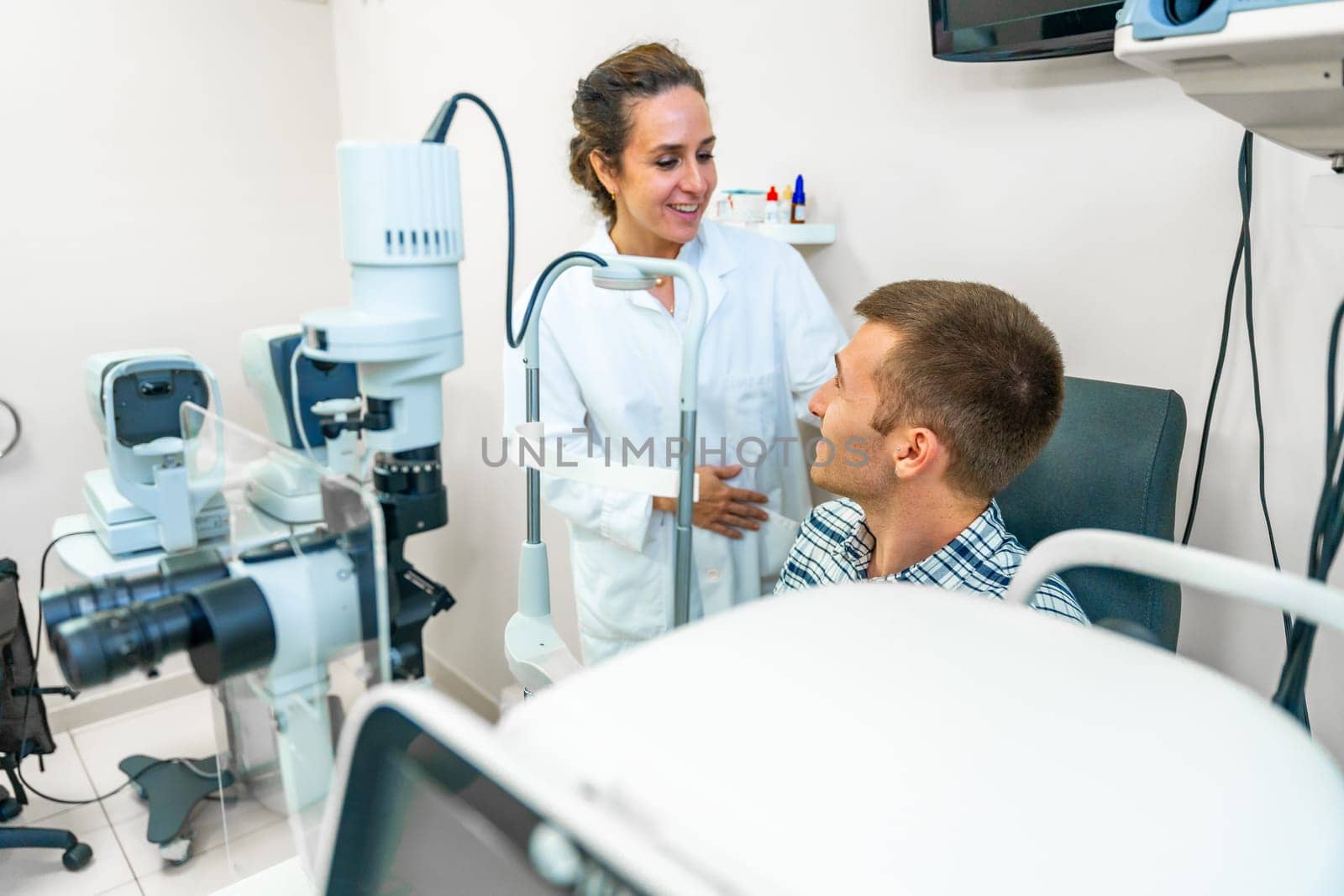 Optometrist talking with a patient in the clinic by Huizi
