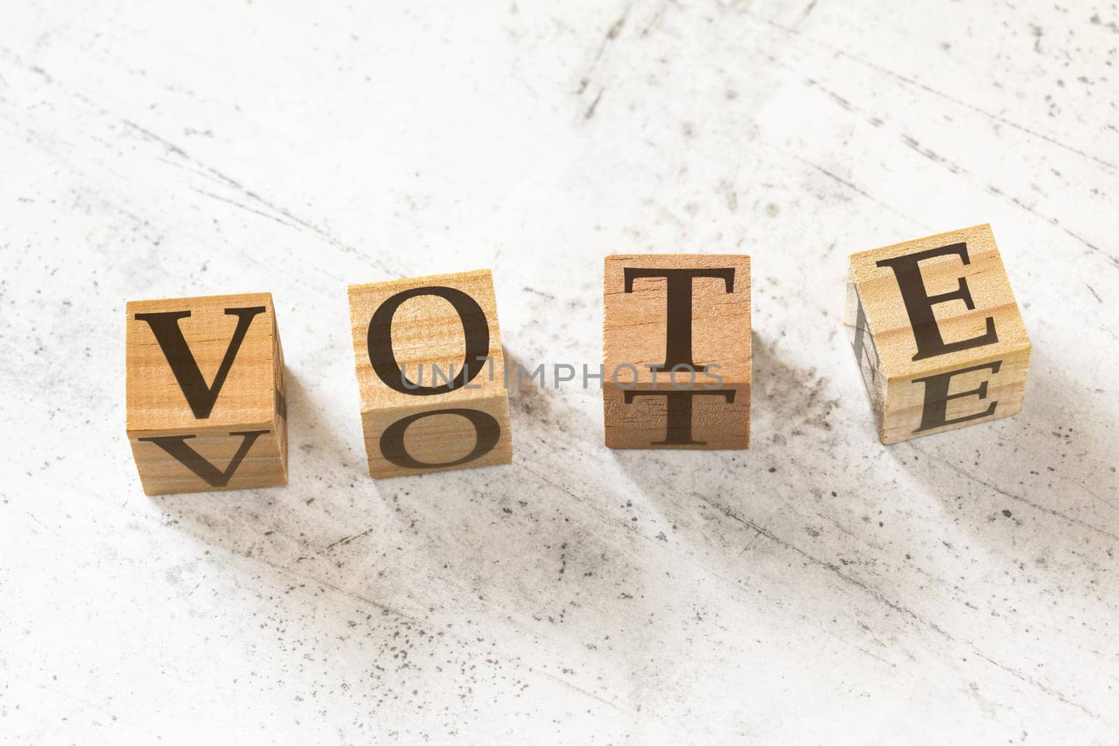 Four wooden cubes with word VOTE on white working board. by Ivanko