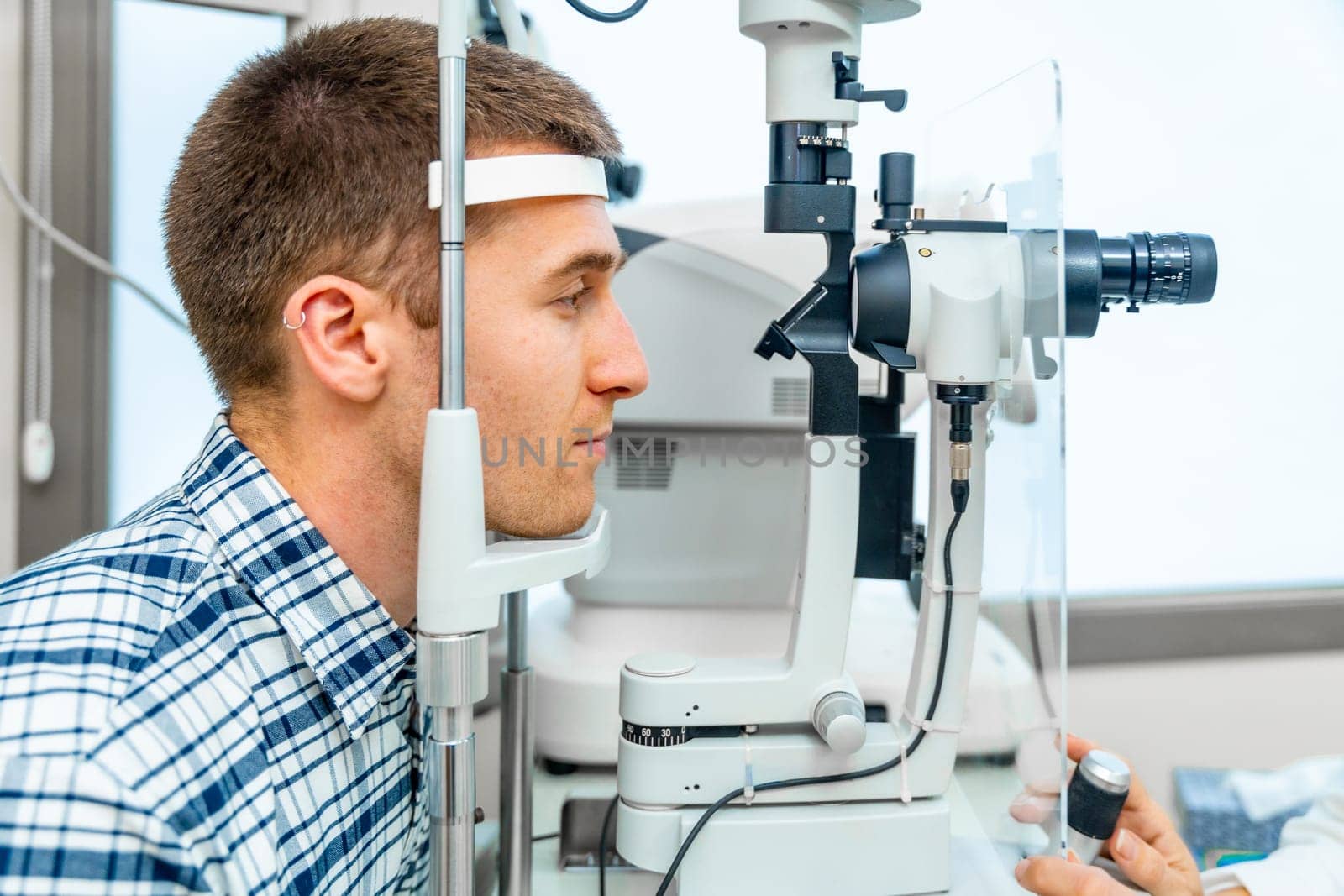 Men patient having a checkup, eye examined by specialist by Huizi