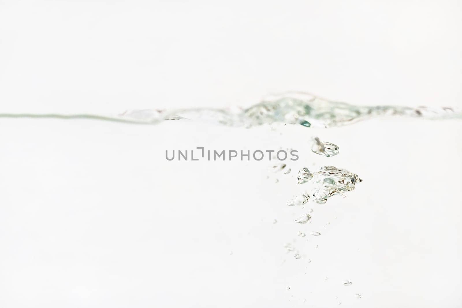 Bubbles in water as its poured into aquarium tank, splashes on surface, white background