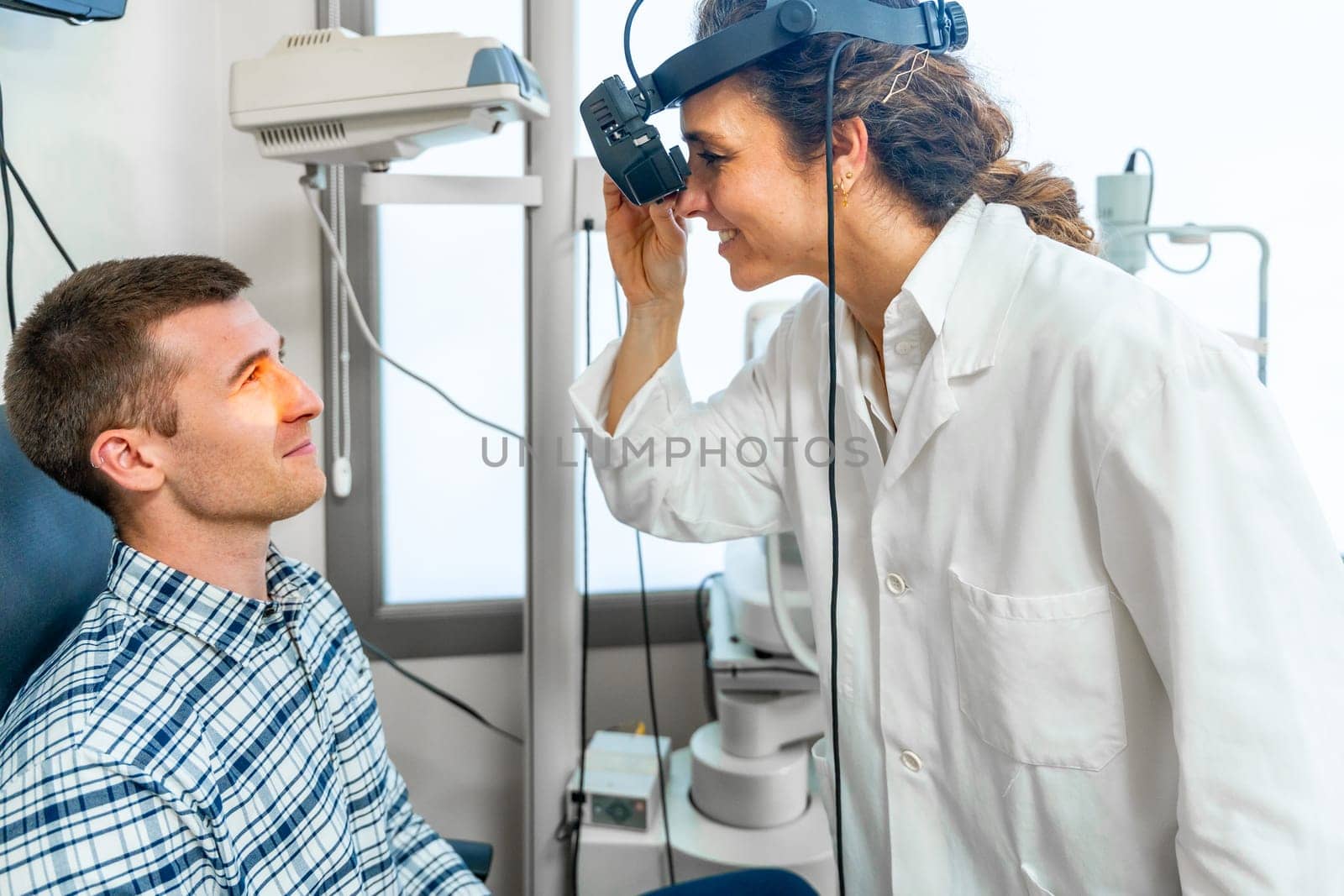Female ophthalmologist checking the retina of a patient by Huizi
