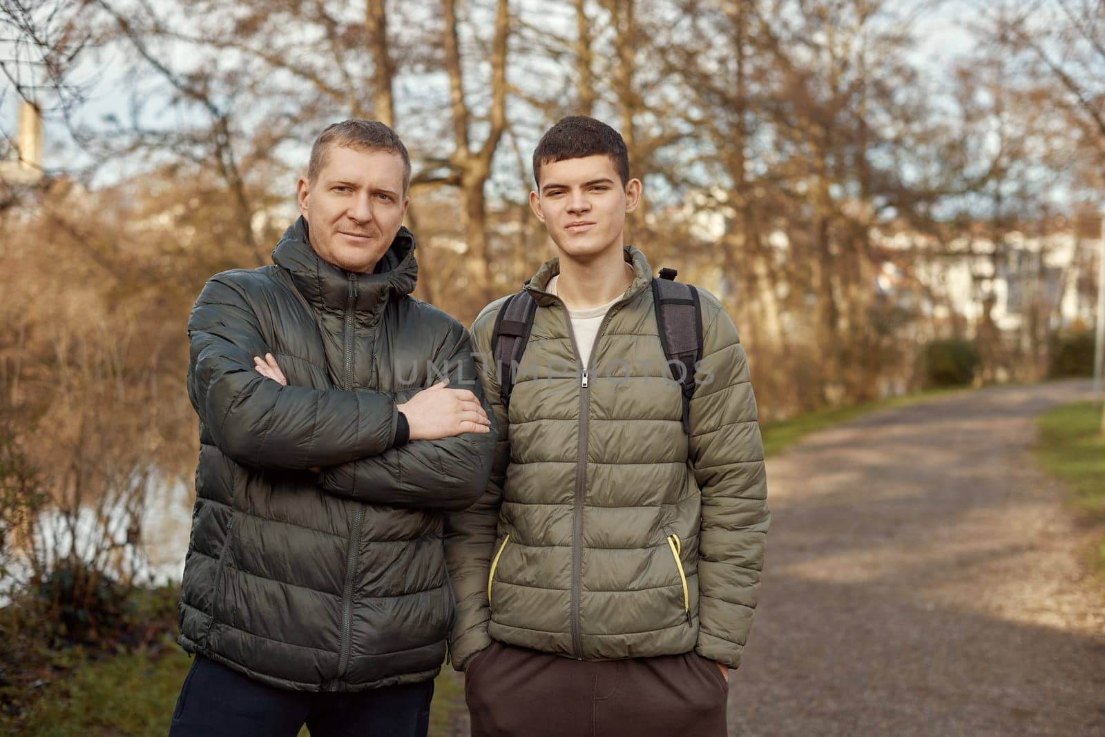 Father-Son Bond: Handsome 40-Year-Old Man and 17-Year-Old Son Standing Together in Winter or Autumn Park. by Andrii_Ko