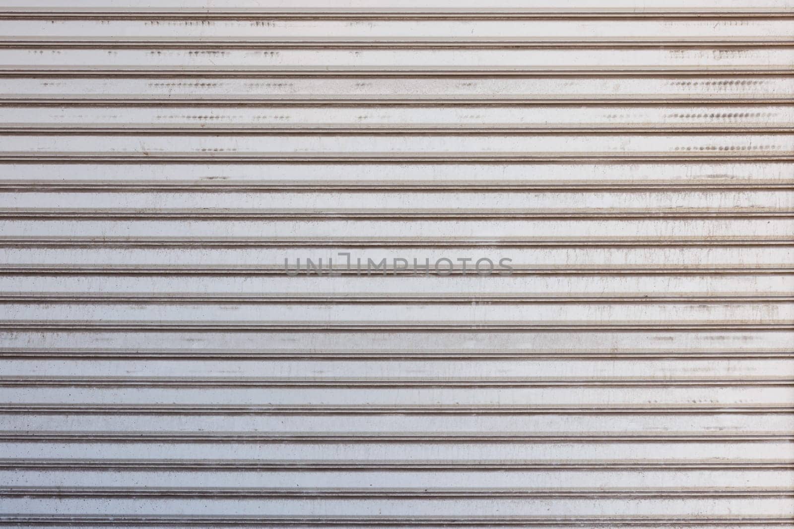 Closeup of a weathered metal shutter with horizontal folding lines by z1b