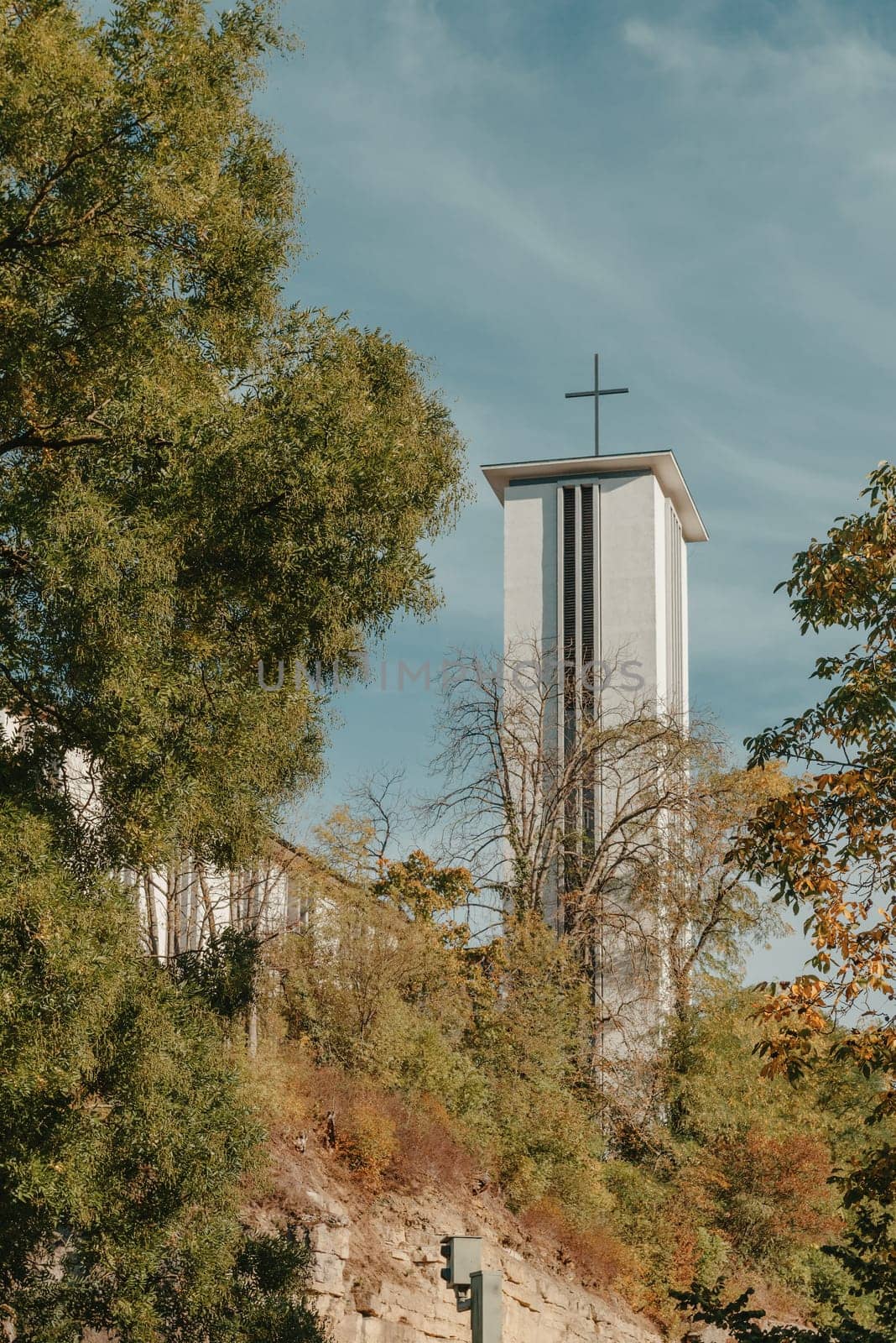 Modern Church Tower with Big Metal Cross. Modern church tower crowned with iron crosses on sunset sky background by Andrii_Ko