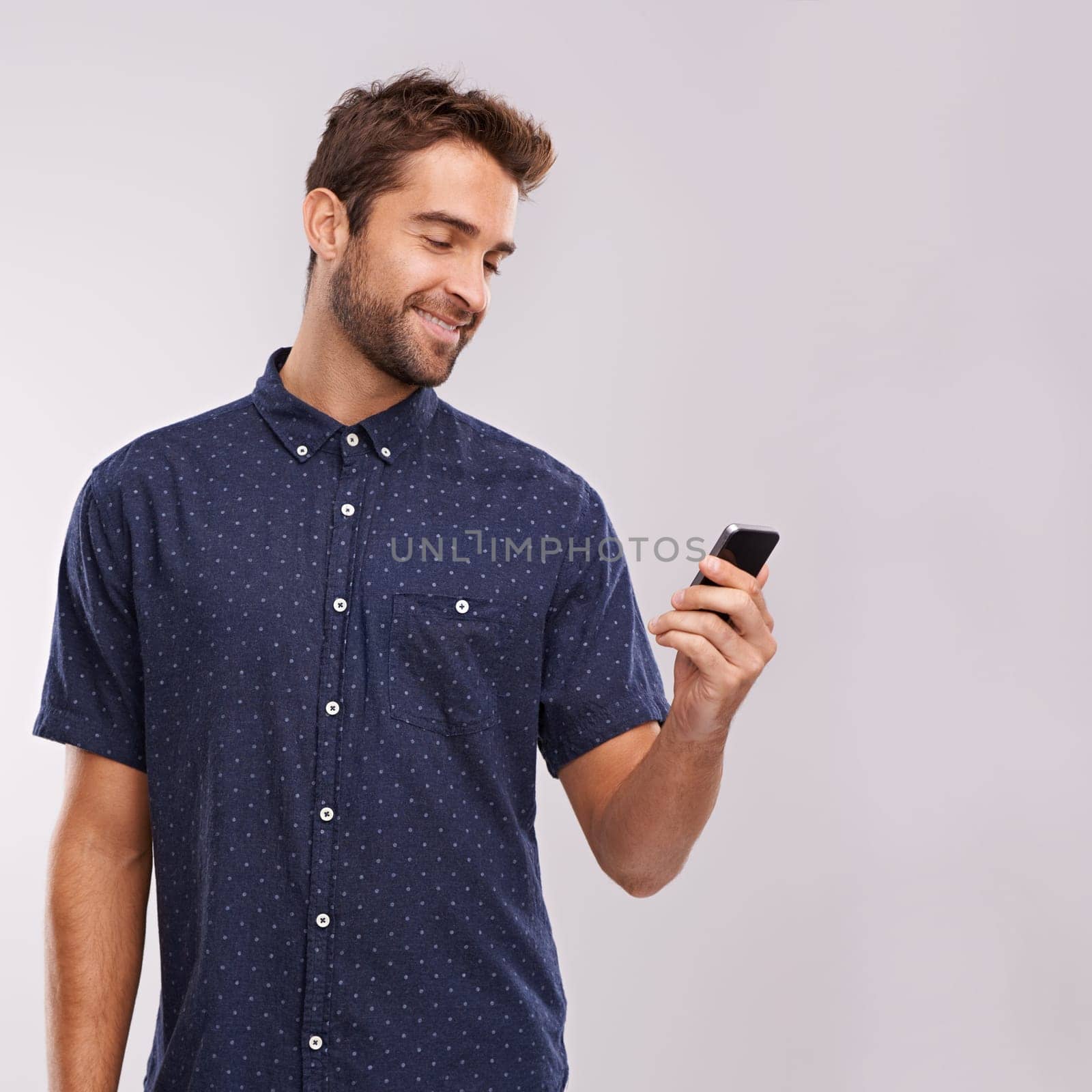 Phone, communication and man networking in studio, background and social media in mockup space. Happy, businessman and reading email on smartphone with news, information or scroll search on internet.