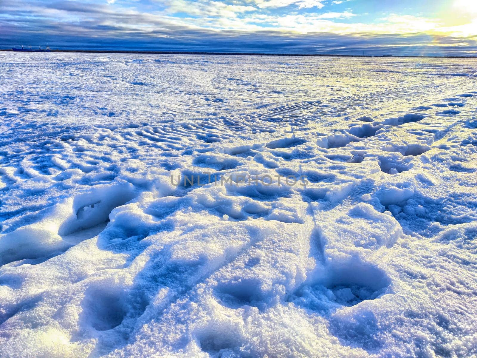 Melting blue snow on the river in early spring. Large snowfield at sunset. Background with landscape, nature