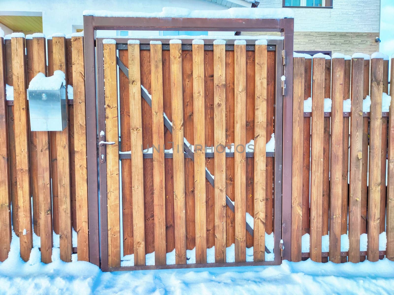 New gate, entrance to a private territory on a winter day and snow. Wooden texture and background. Fence