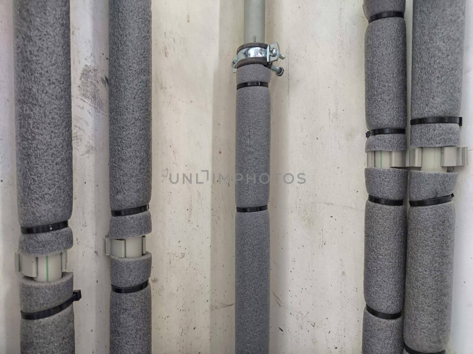 Close-up of insulated plumbing pipes. Insulated Pipes in Public Restroom on the wall