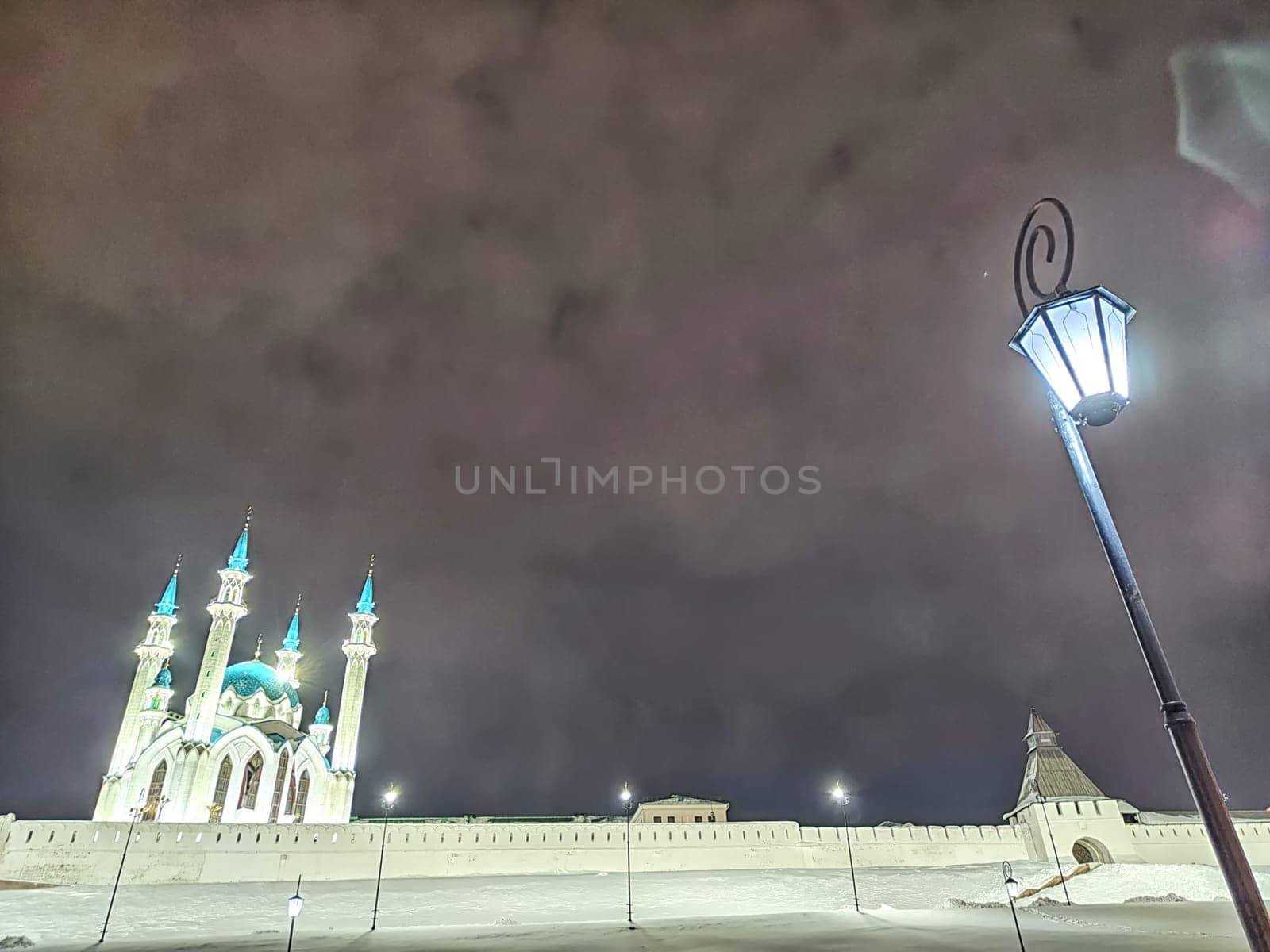 Beautiful white mosque with minarets against dark cloudy sky in night or evening. Ramadan Holiday