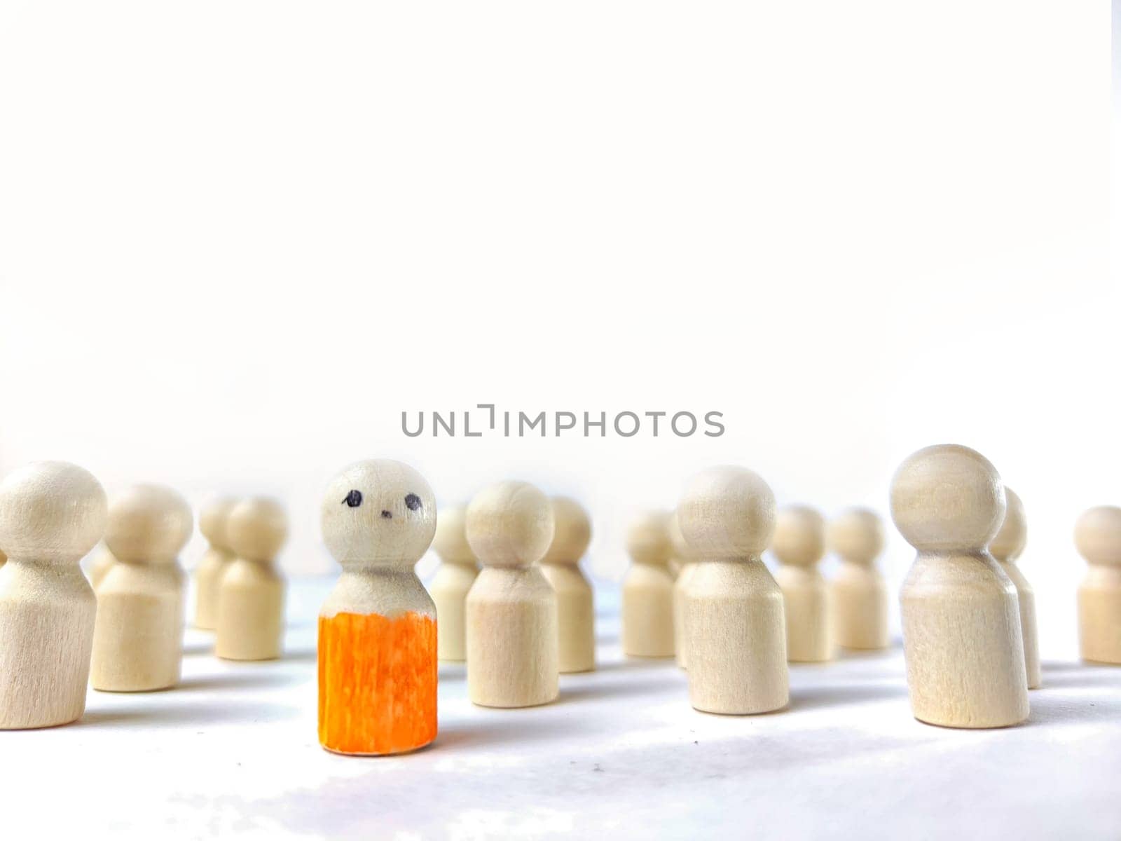 Wooden figurines with a leader and group with partial focus. The concept of distinguishing a leader from the crowd. Sighted, intelligent, different among the blind group