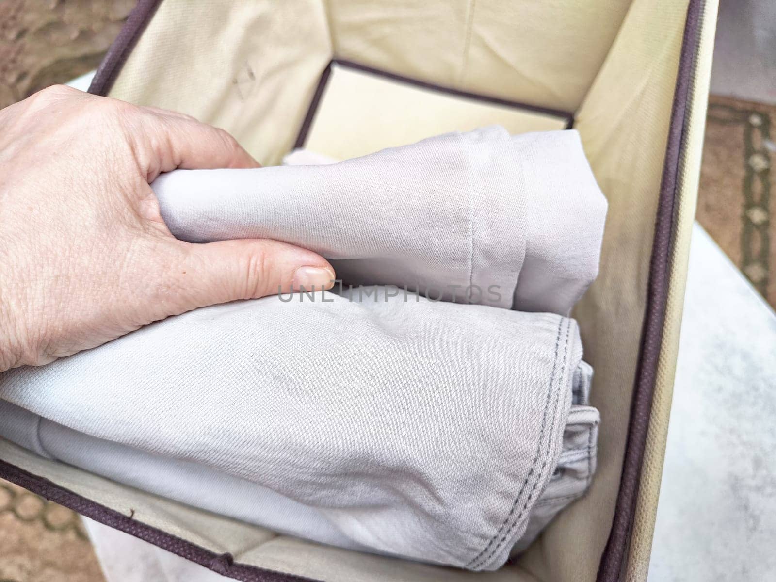 Organized Clothing Storage Using Konmari Folding Method. Neatly folded clothes arranged vertically in a storage box