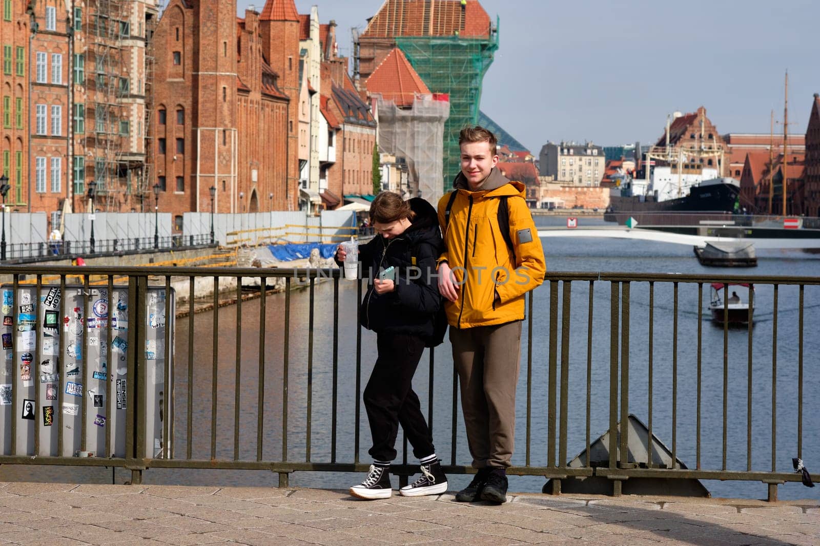 A young girl and a young man on a bridge near the water