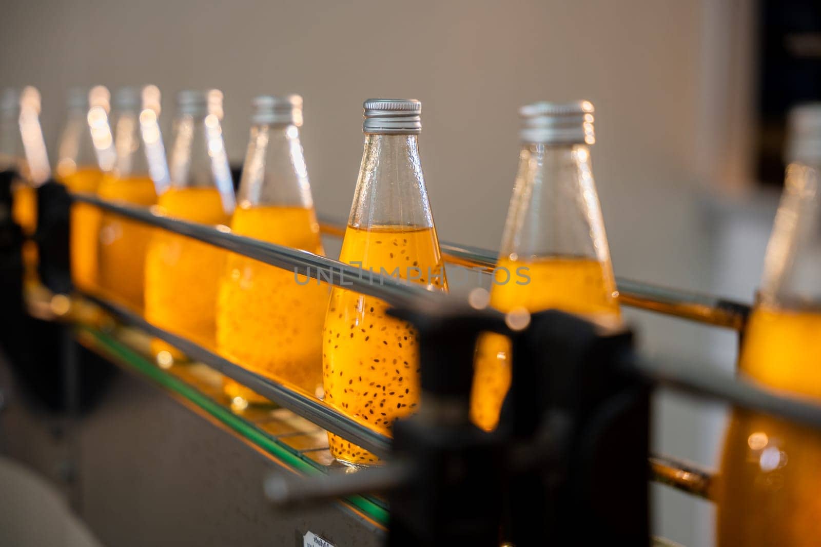 Basil or chia seed beverages with pomegranate undergo quality filling into transparent bottles by Sorapop