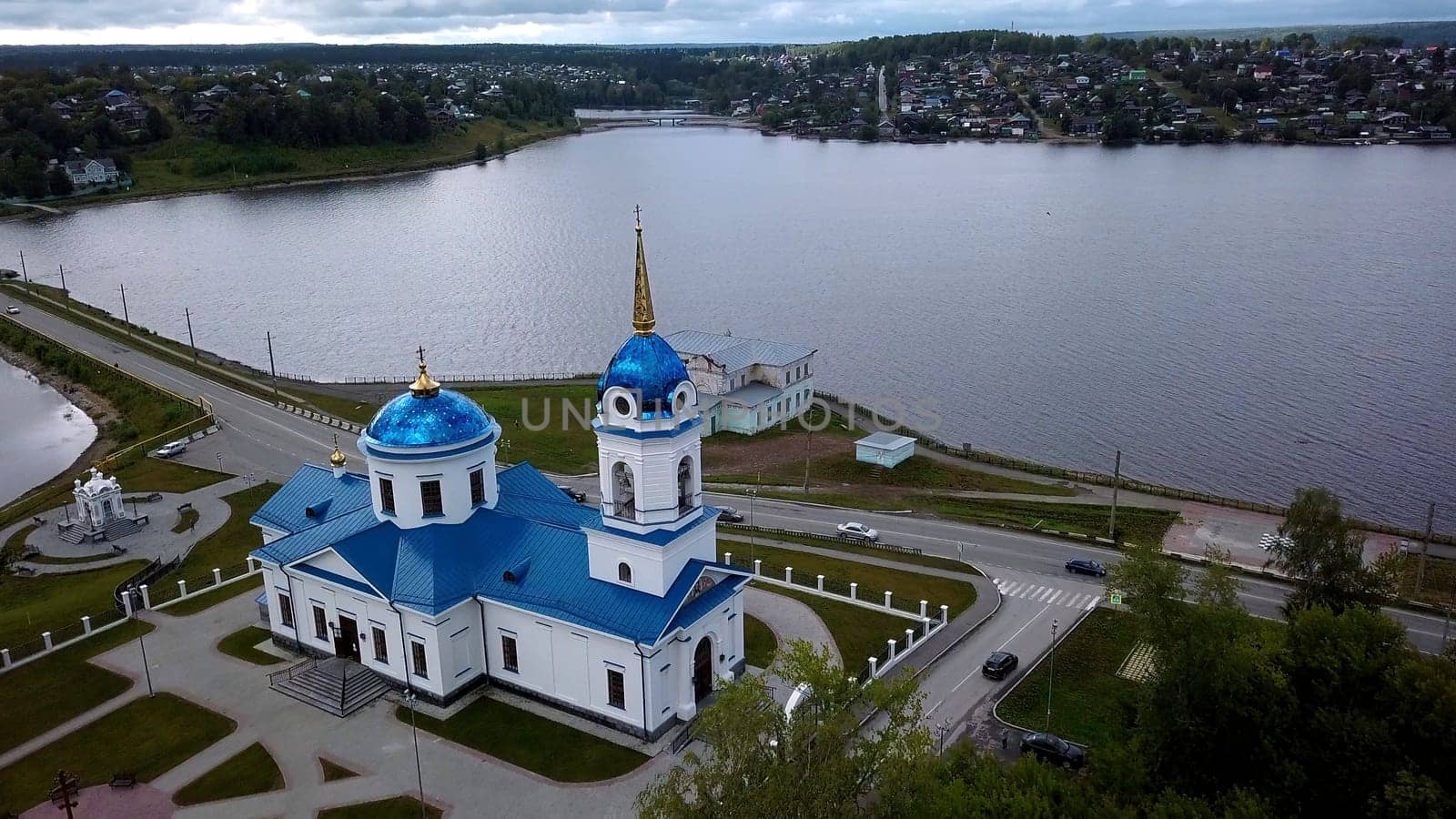 Panoramic aerial view of monastery on a summer day. Clip. Beautiful white church with blue roof near pond