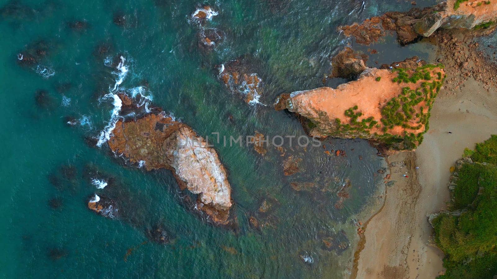 Top view of beautiful wild coast with rocks in water. Clip. Coastline with rocks and waves near shore. Inspiring nature of sea coast with variety of rocks.