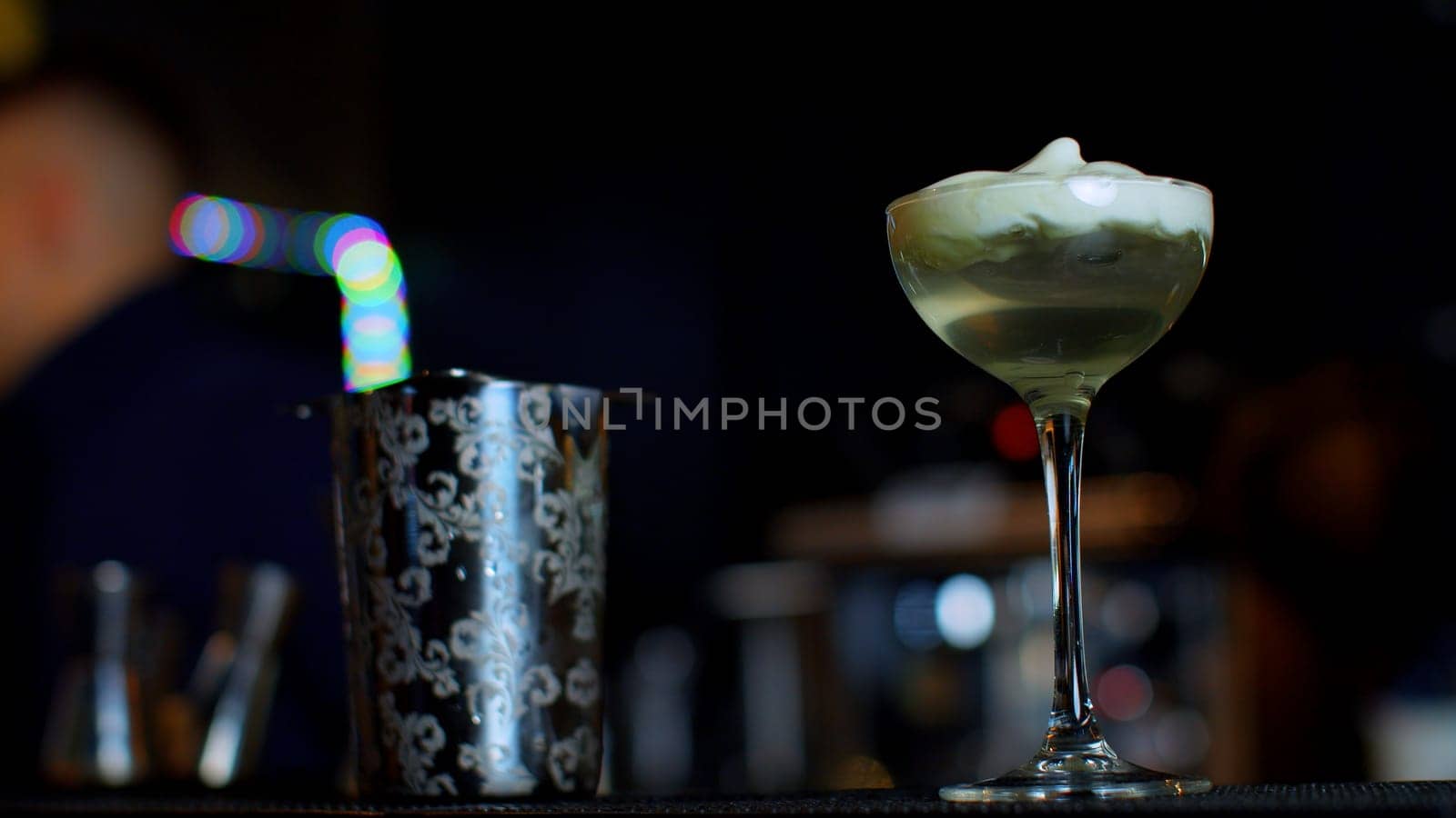 A professional bartender preparing an alcoholic cocktail with cream topping. Media. Making a beverage at the bar or disco club. by Mediawhalestock