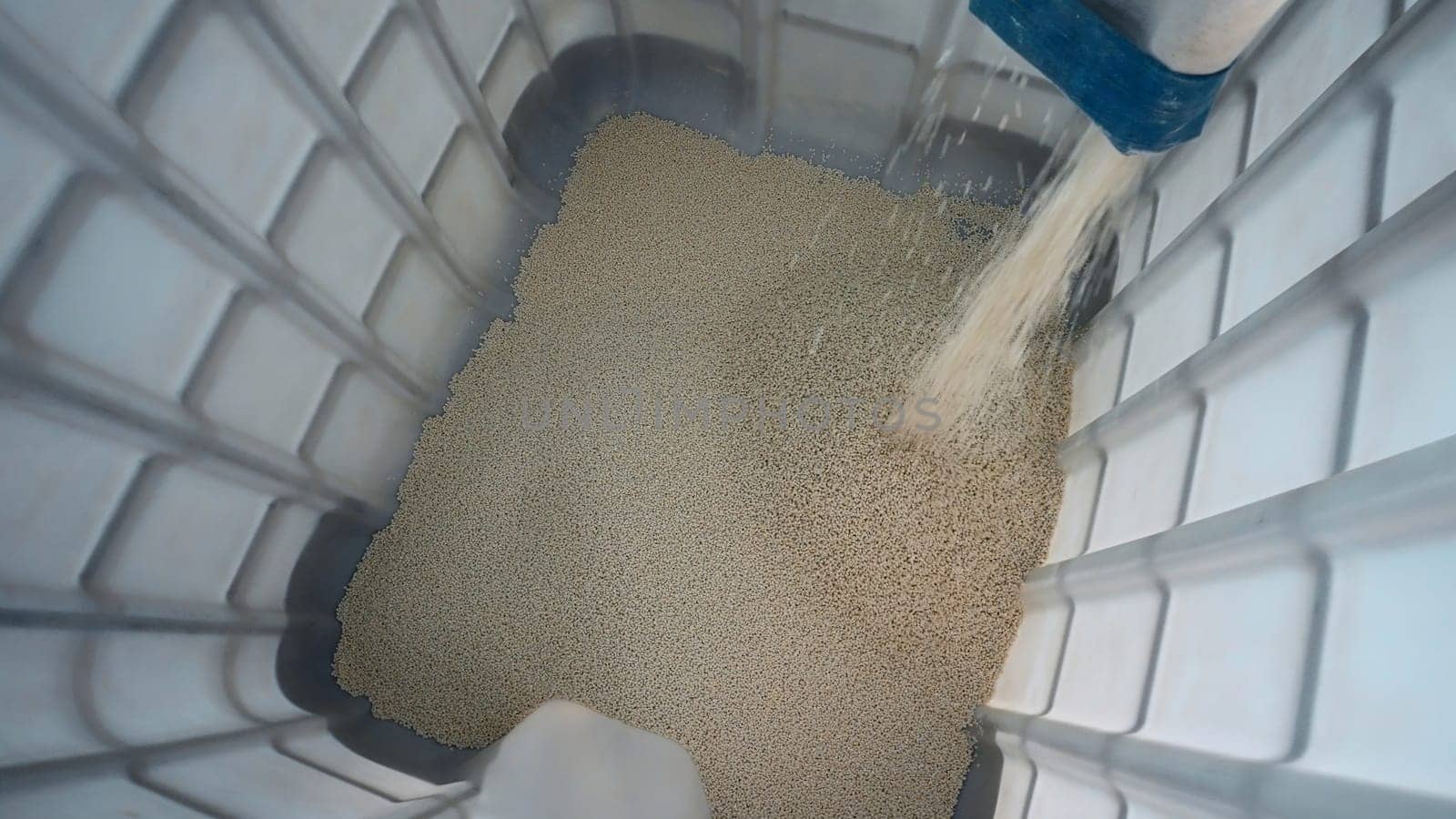 Pouring pile of plastic particles. Creative. Process of filling containers and cleaning plastic particles. Plant for processing chemical granules of plastic.