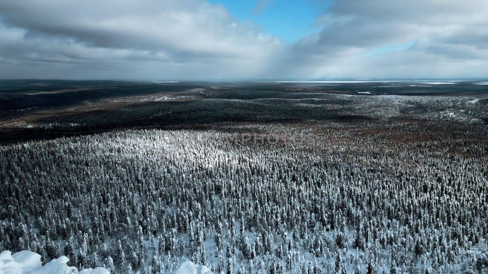 A flight over the dense winter Siberian forest in the afternoon. Clip. White mountain and a frozen weather tower on its top. by Mediawhalestock
