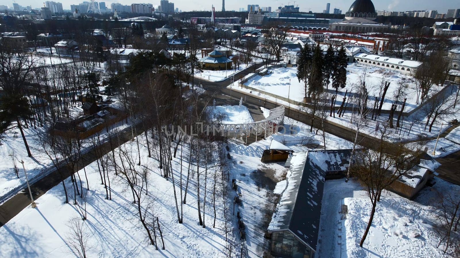 Top view of suburb with greenhouses on winter day. Creative. Suburban infrastructure on background of horizon with modern city. Agriculture and cottage settlement in suburbs on sunny winter day.