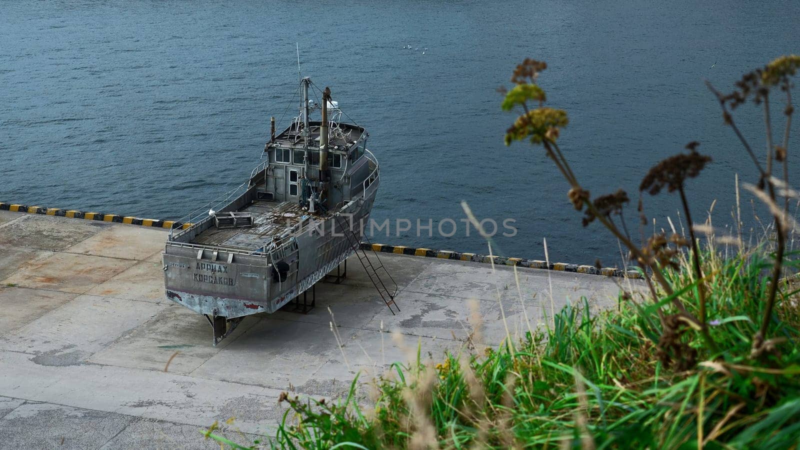 Old abandoned ship on seashore. Clip. Abandoned wooden ship stands on embankment platform. Salvaged old abandoned ship on seashore.