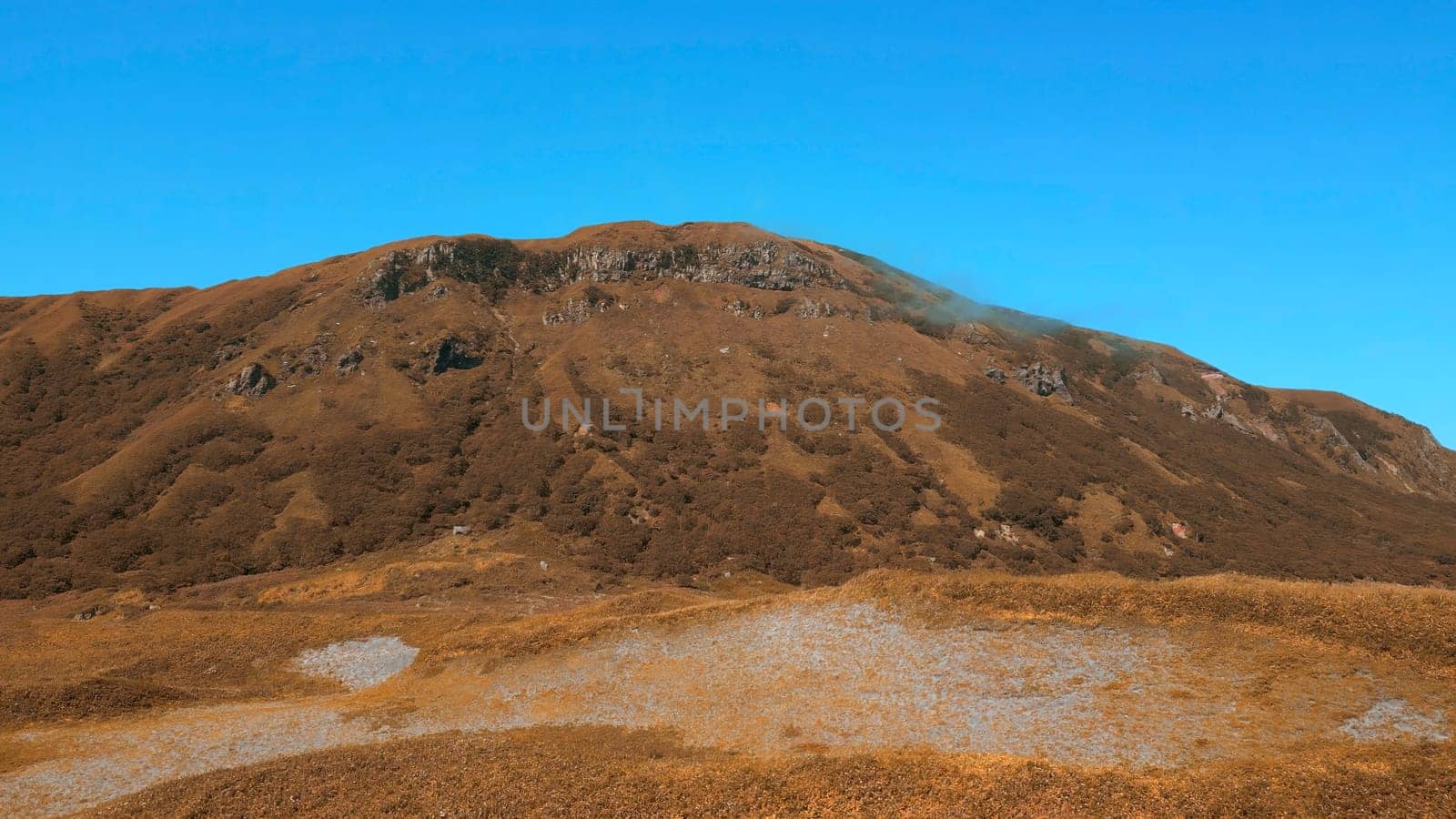 Colorful autumn vegetation in a mountainous area. Clip. A sunny day, blue sky and golden hills. by Mediawhalestock