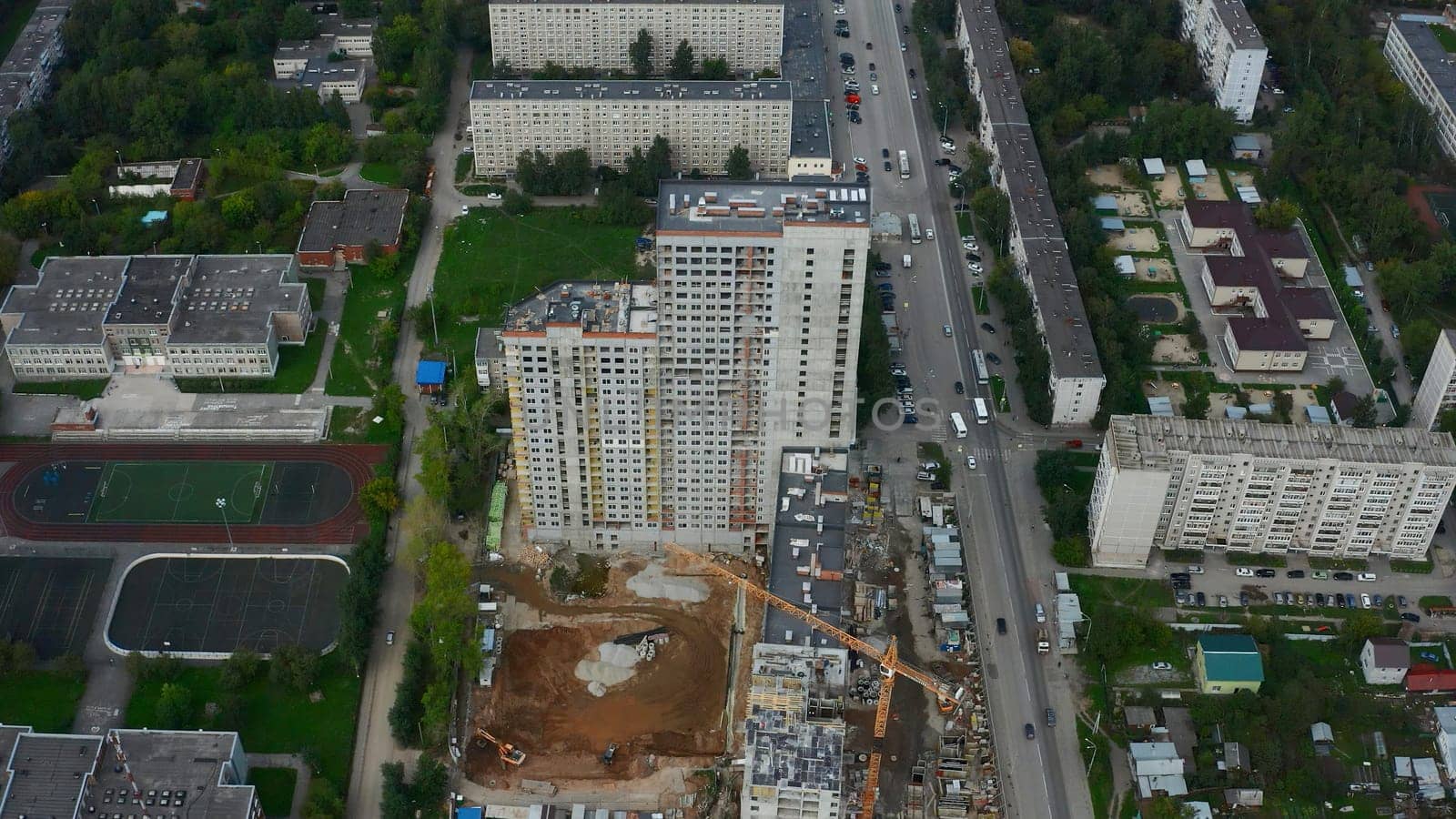 Top view of construction of multi-storey building in city. Stock footage. Construction of multi-storey building in city center on summer day. Panorama of modern city with construction of high-rise buildings.