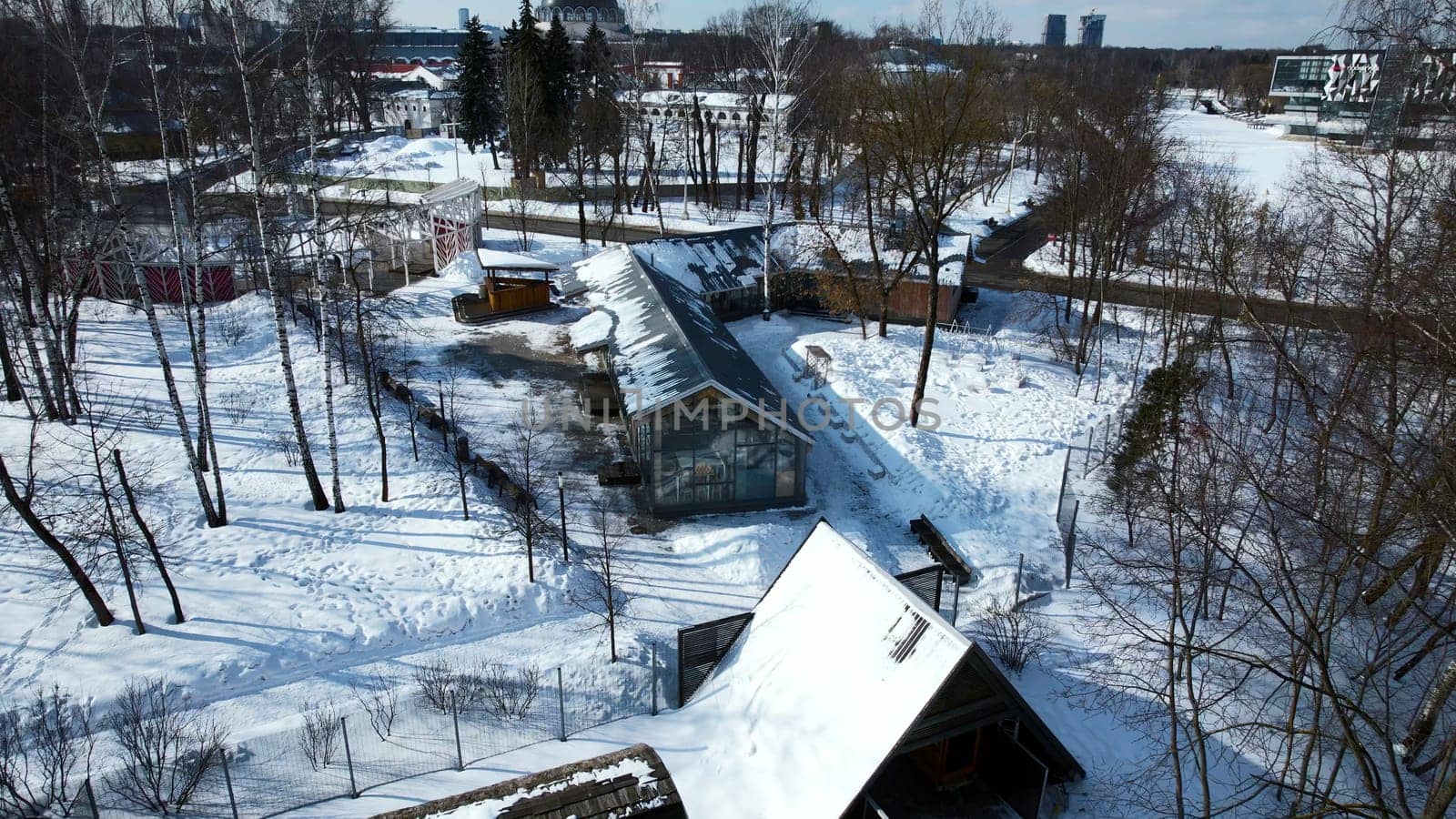 Top view of suburb with greenhouses on winter day. Creative. Suburban infrastructure on background of horizon with modern city. Agriculture and cottage settlement in suburbs on sunny winter day by Mediawhalestock
