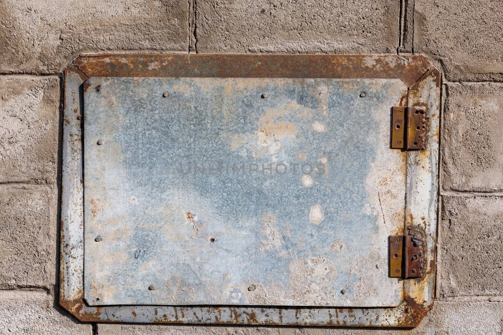 A small rectangular zinc coated metal hatch mounted on a brick wall, flat texture and background