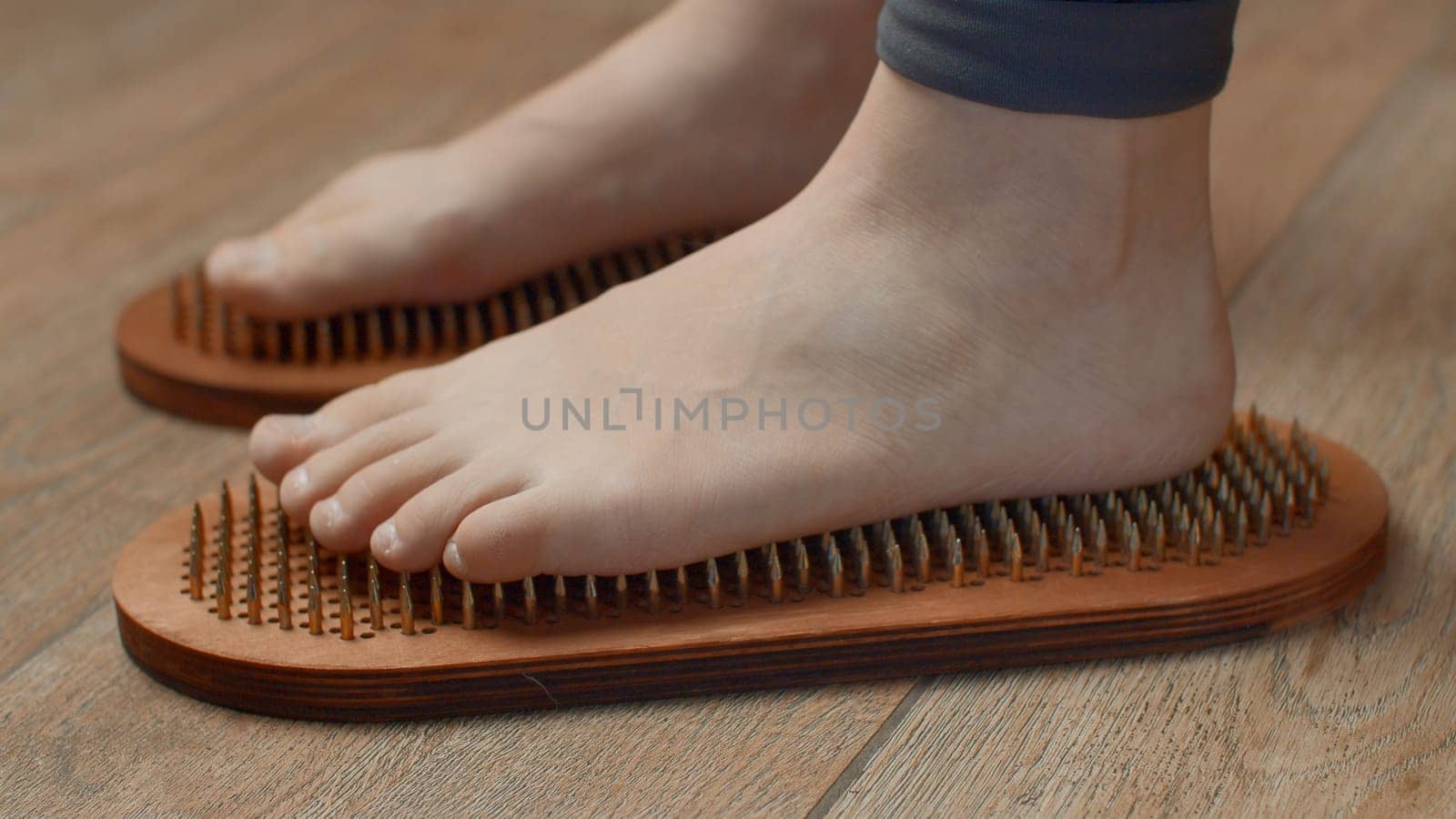 Female feet standing on boards with nails, close up. Media. Barefoot female standing on yoga nails board