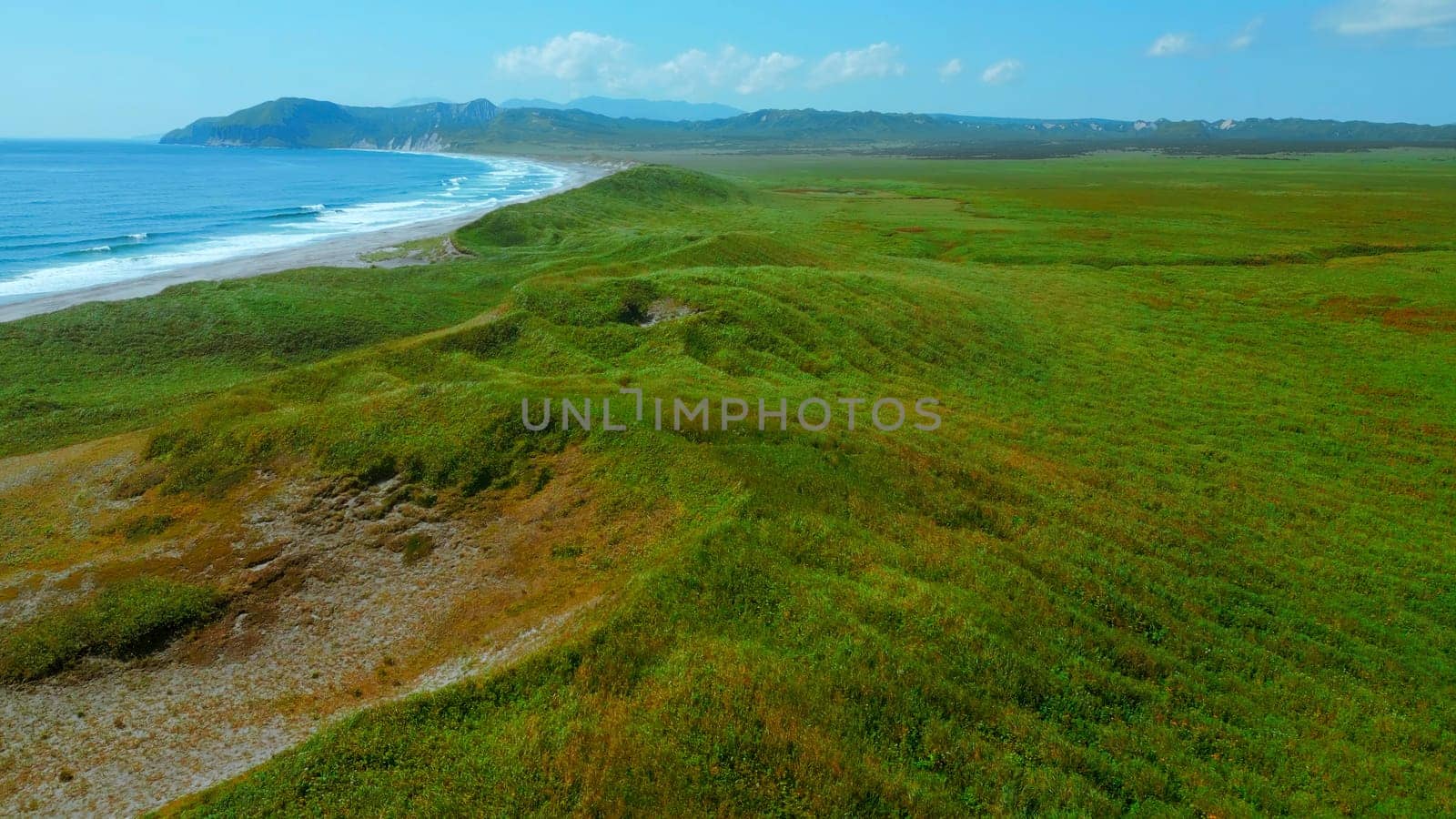 Aerial view of summer green meadows and mountains at the edge of the sea on the Isle of Skye, Scotland. Clip. Concept of summer nature