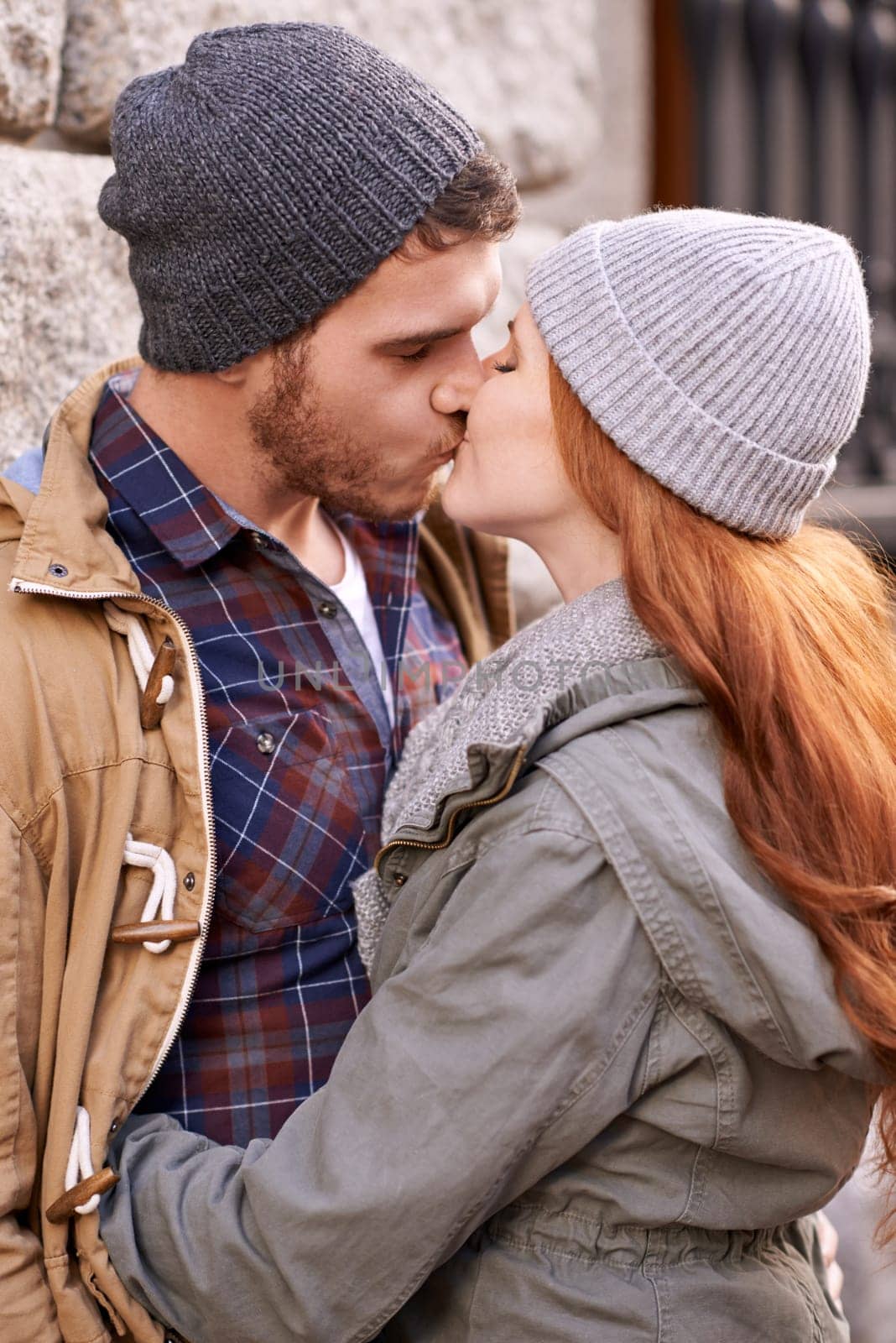 Couple, love and kiss with closeup in outdoor in against wall on cold weather, together and support in London. Affection, relationship and bonding for romance with soulmate, care and happiness.