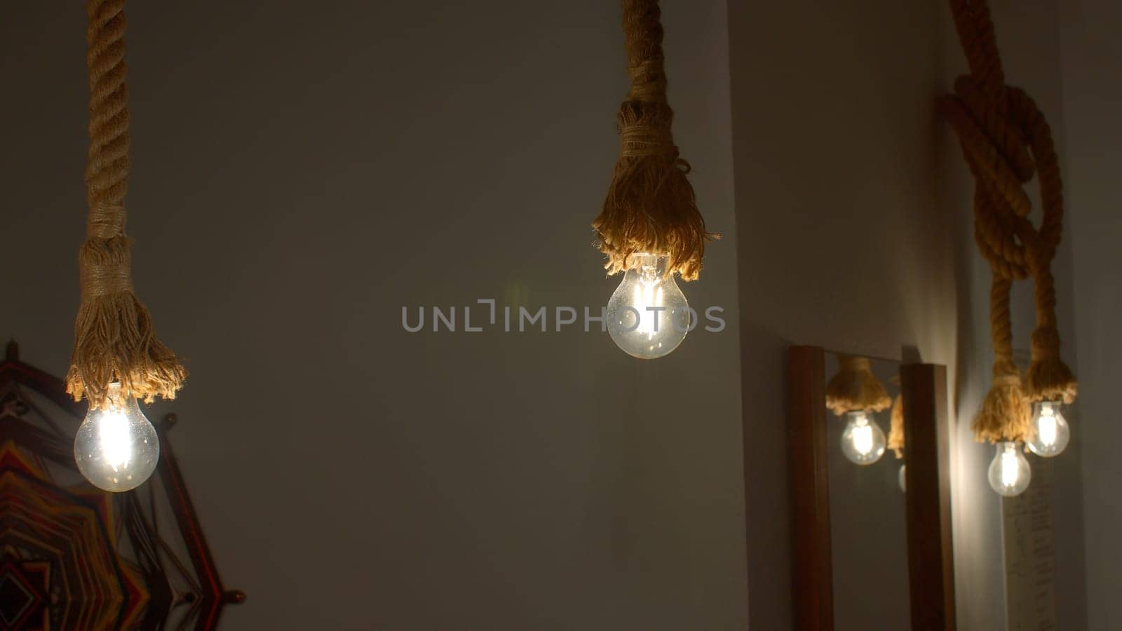 Burning stylish light bulbs decorated by ropes. Media. Stylish hanging bulbs, ethnic interior. by Mediawhalestock