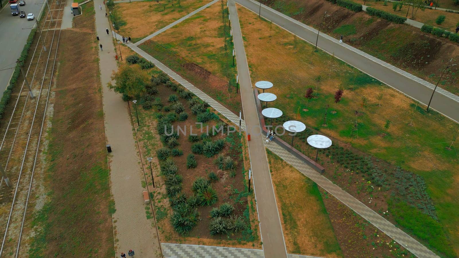 Top view of people walking in park alley in city. Clip. People walk and relax in modern city park. Landscape of city park alley with solar panels.